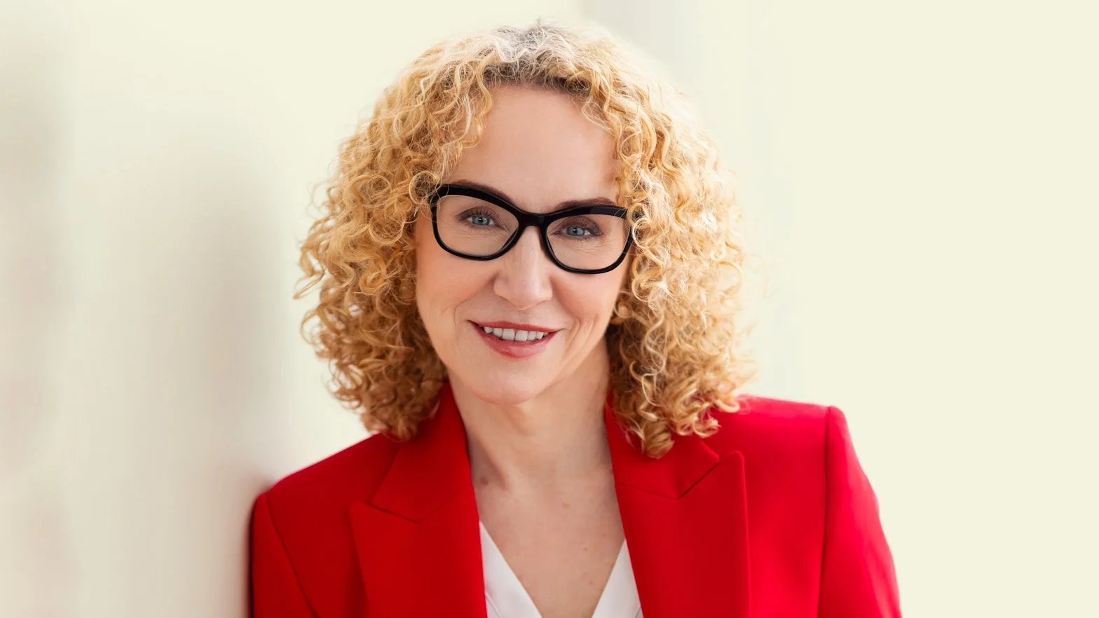 Mila Apostolovic, menopause coach and founder of Unlimited by Mila, smiling confidently in a red blazer.