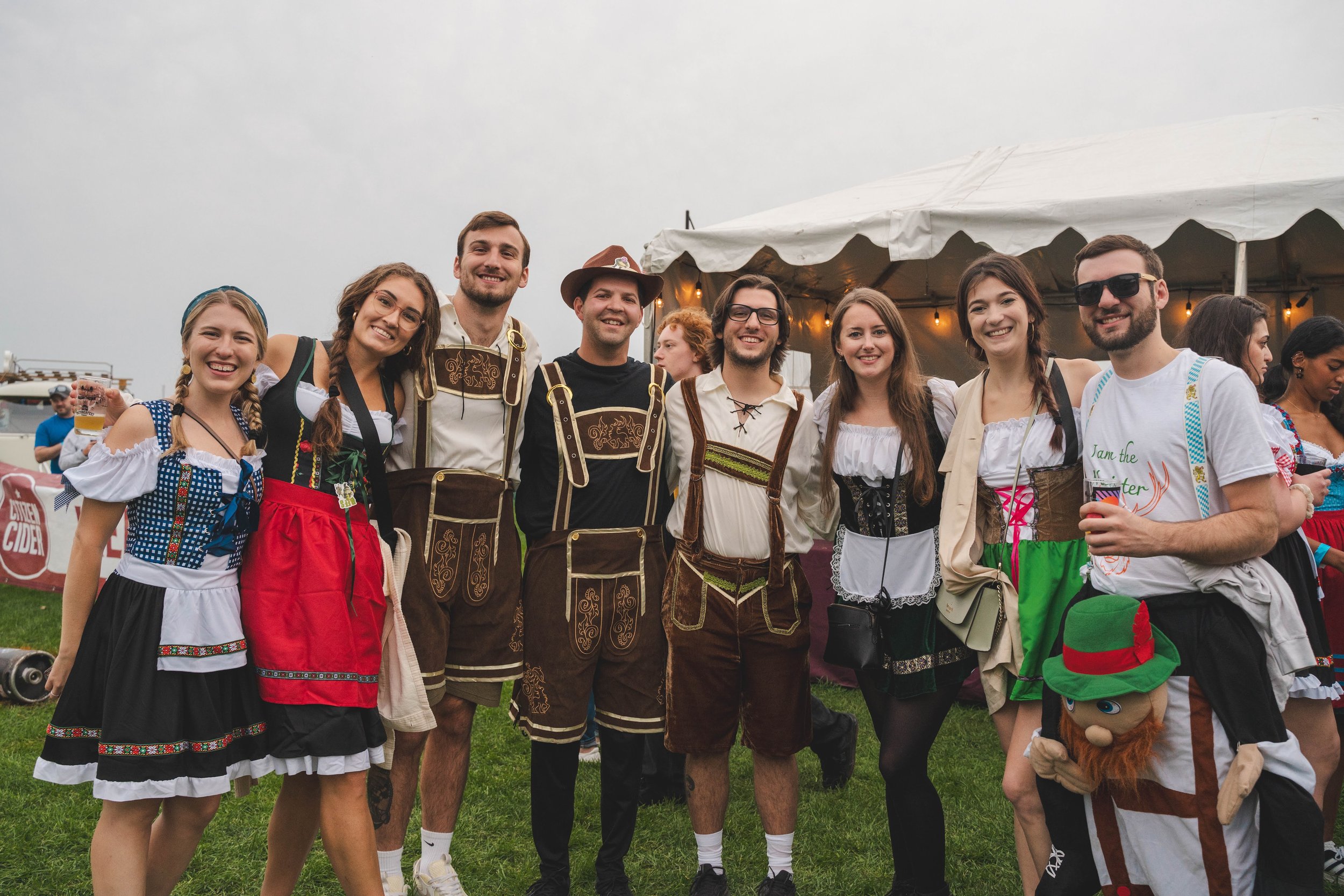 Group of people dressed in traditional German attire at an outdoor festival.