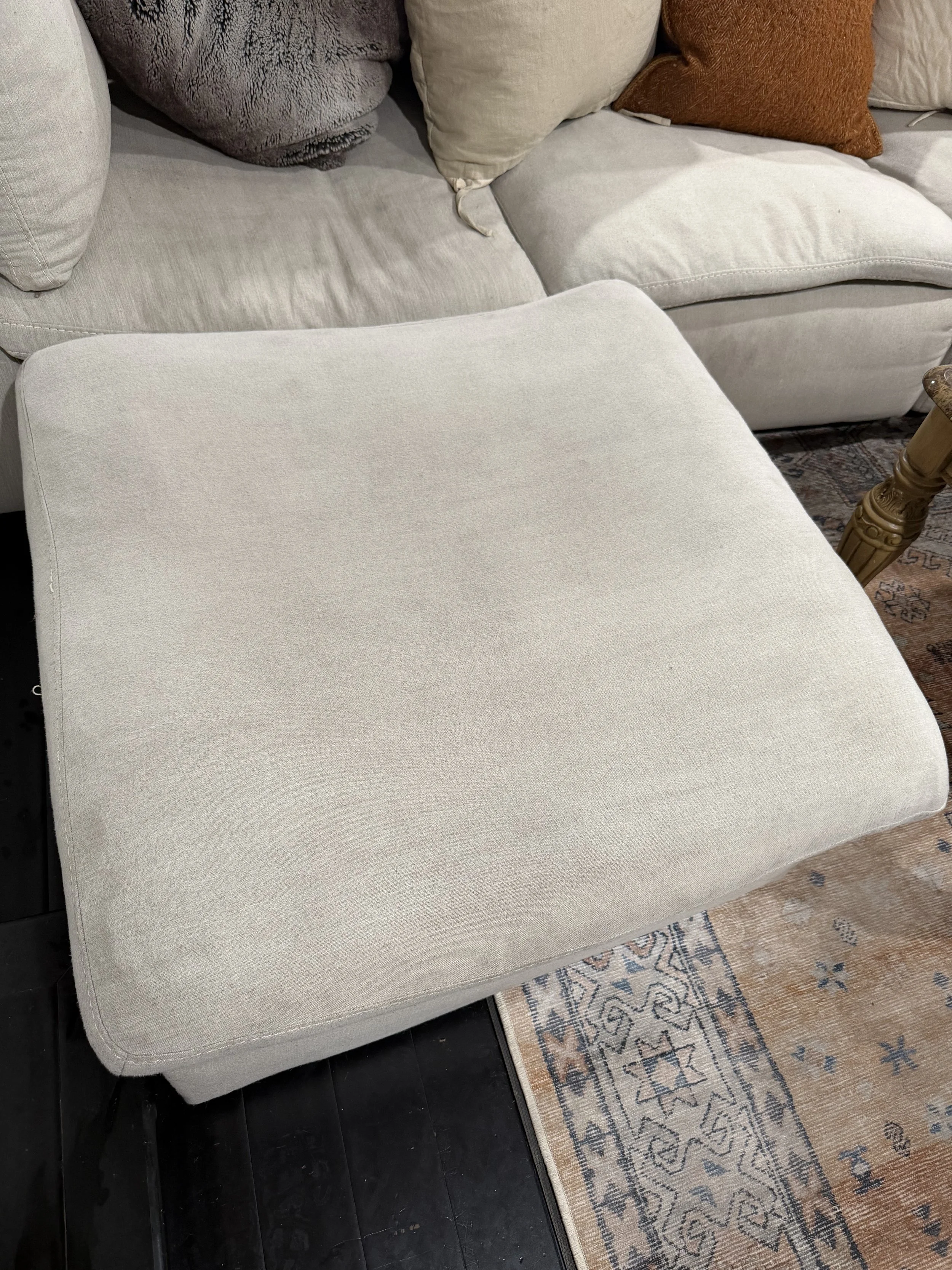 A restored back to its cream-colored ottoman, without stains and back to its original shape. 