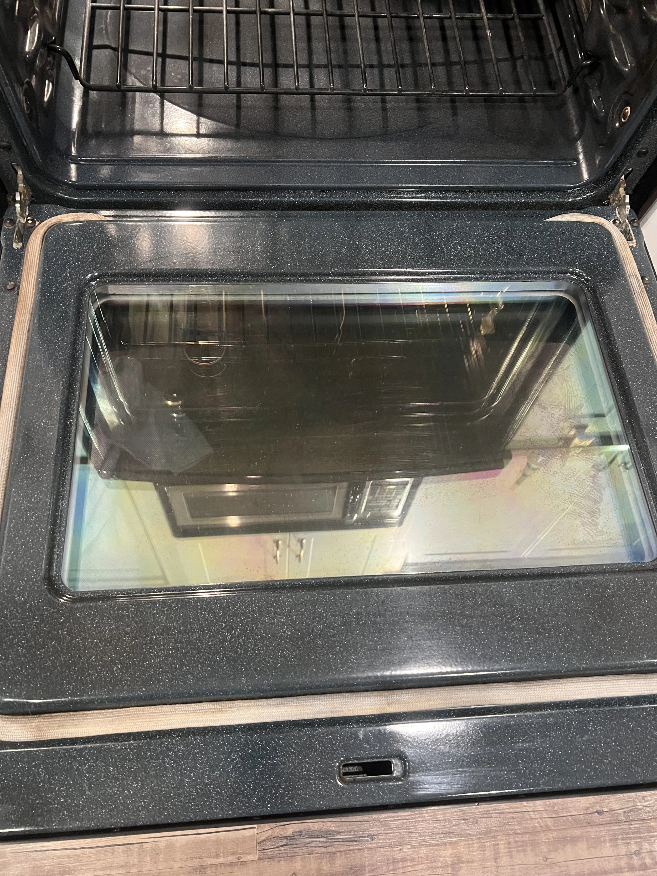 Top view of a modern black oven with a glass door, oven rack, and control panel.