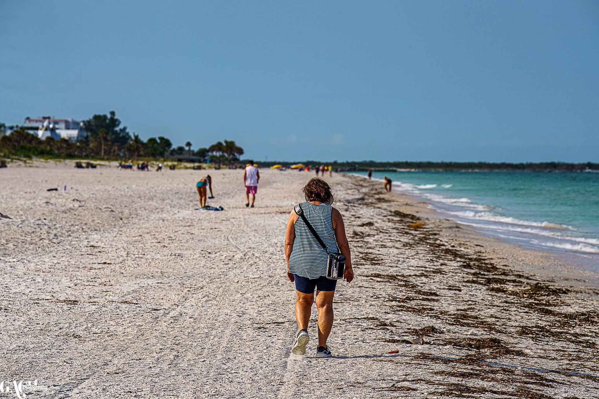 People walking and relaxing on a sandy beach by the ocean.