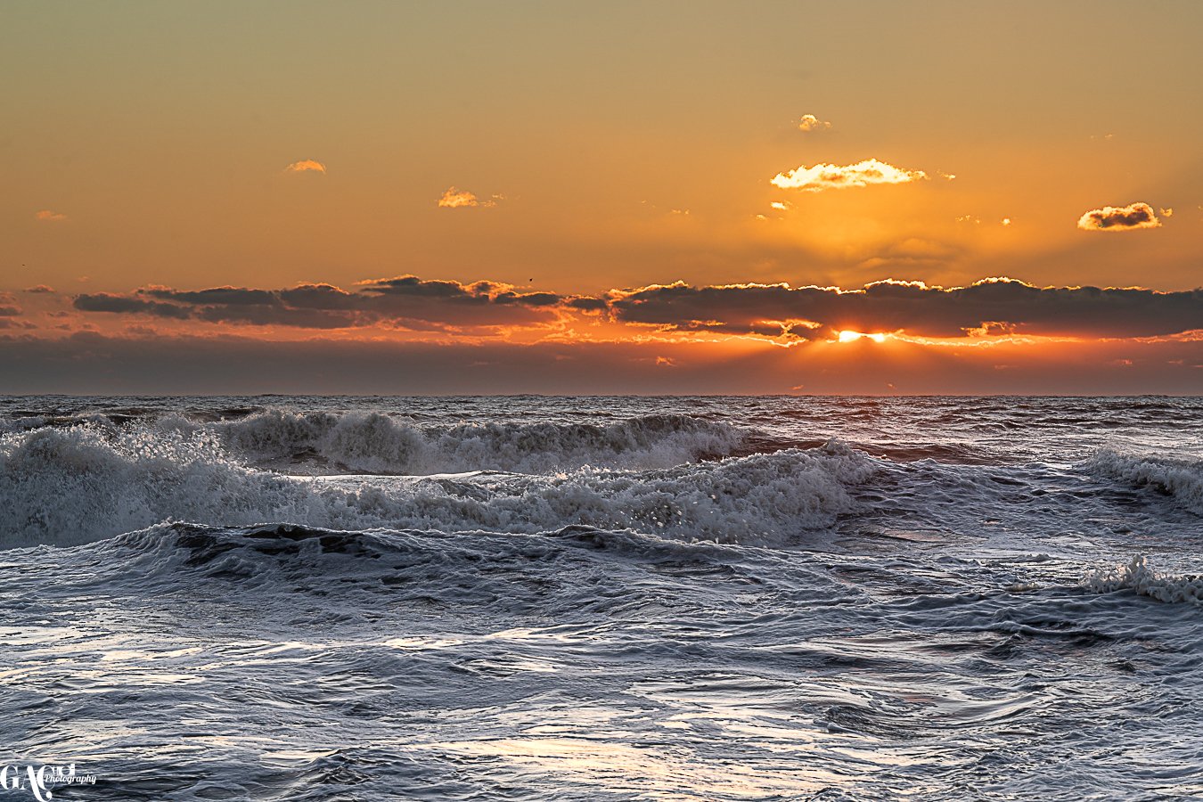Ocean waves crashing during sunset with clouds in the sky