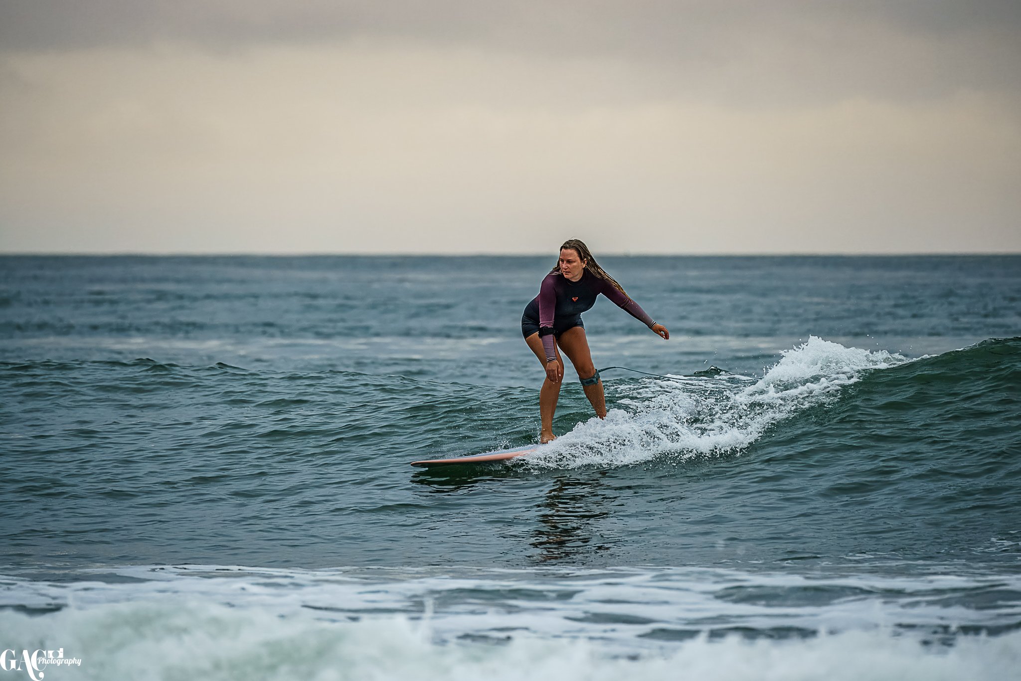 A woman surfing on a wave in the ocean during daytime.