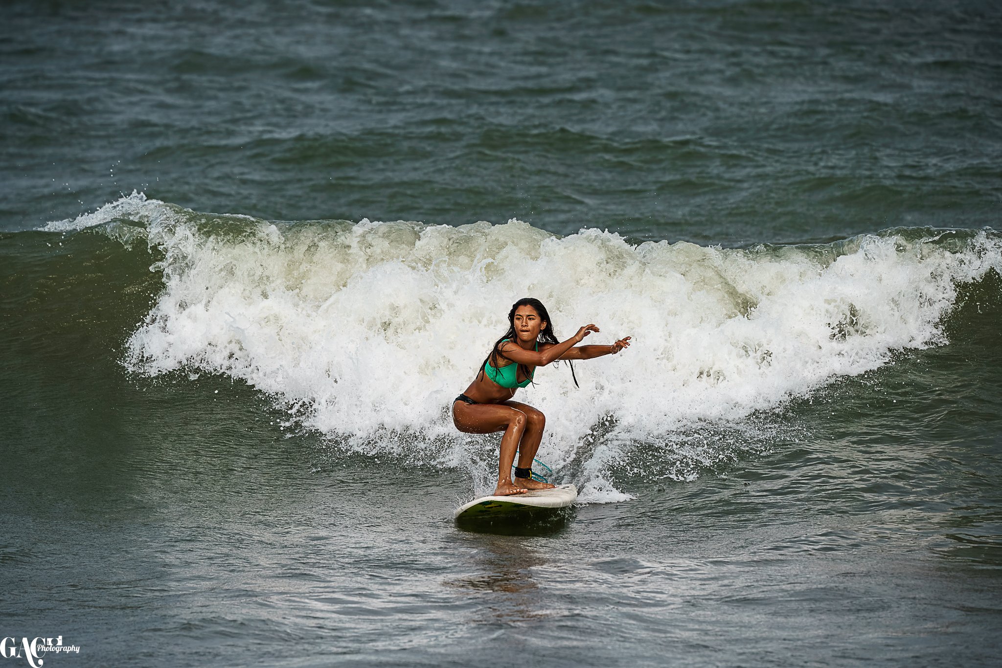 A woman riding a surfboard on a wave in the ocean.