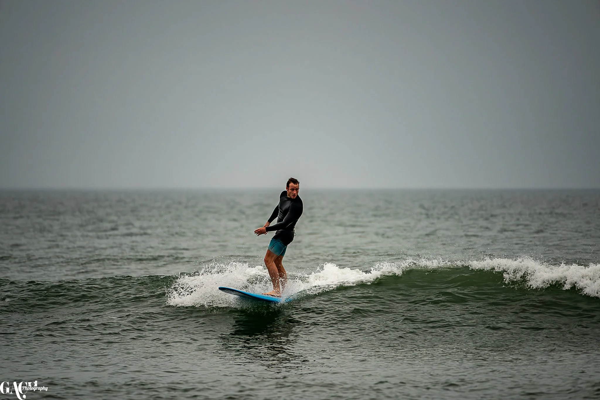 Man surfing on the ocean during overcast day.