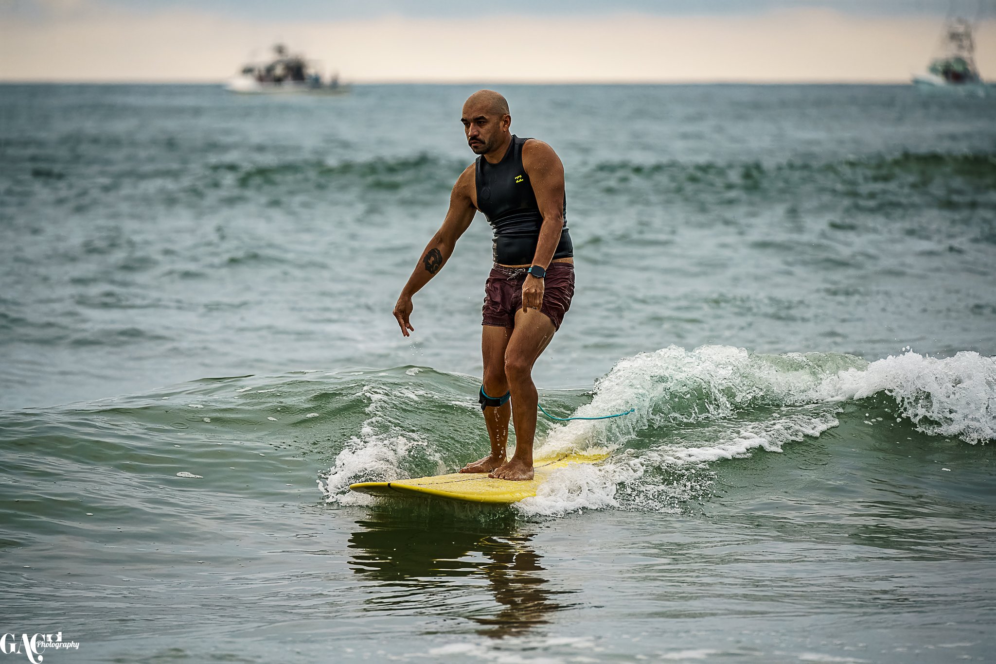 A man riding a yellow surfboard on small waves at the beach during daytime.