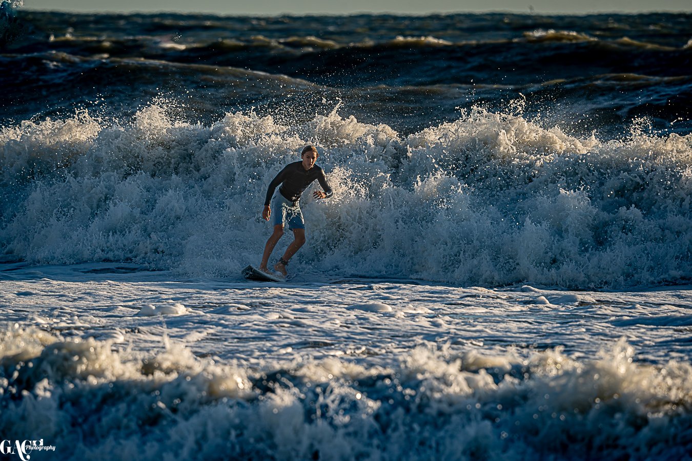 Young person surfing on a wave at the beach during sunset.