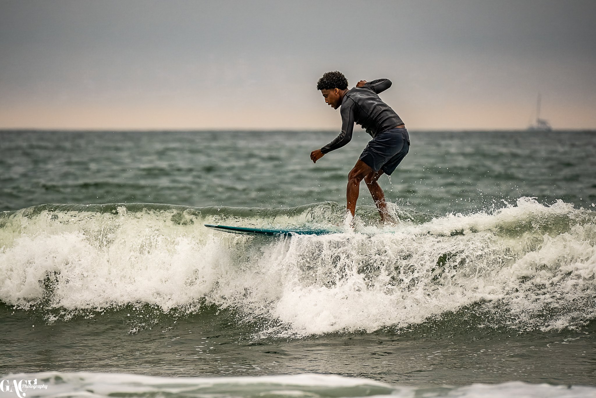 Man surfing on a wave in the ocean during overcast weather.