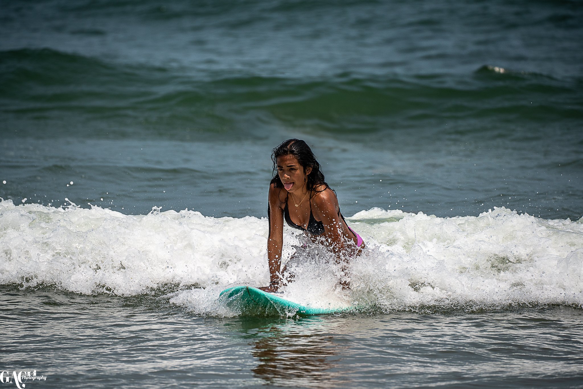 A woman riding a surfboard on small waves at the beach.