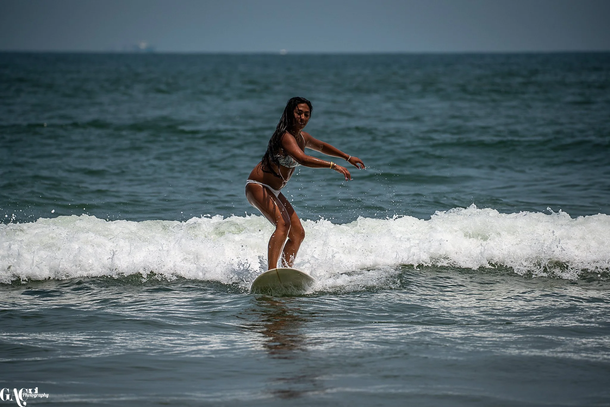 Woman surfing on a wave in the ocean, wearing a bikini.