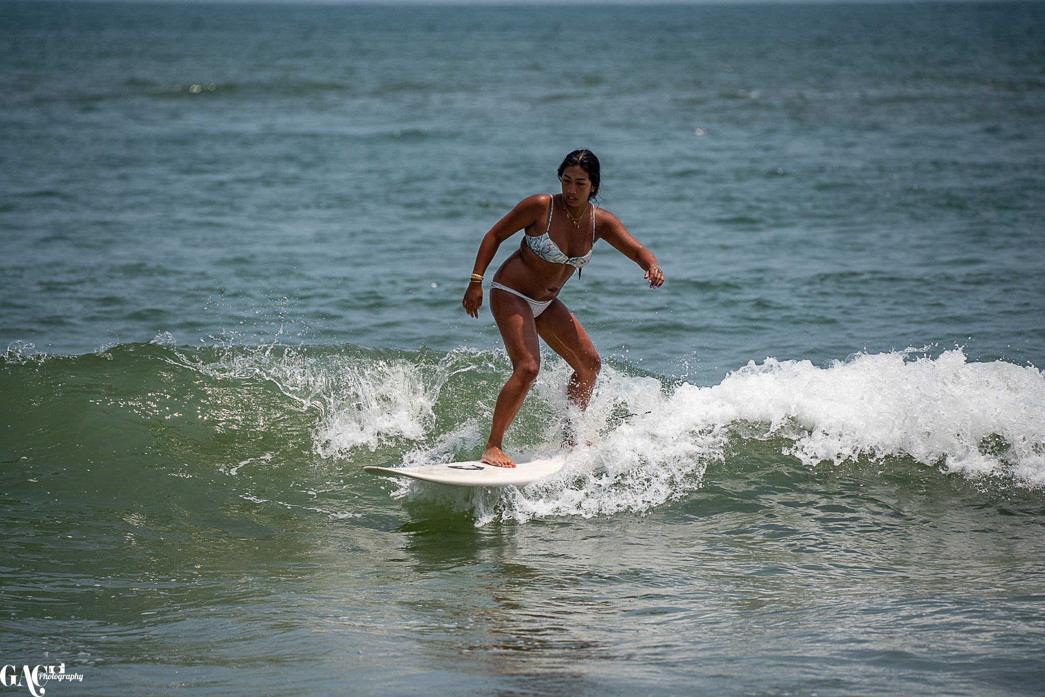 A woman in a bikini surfing on a small wave in the ocean.