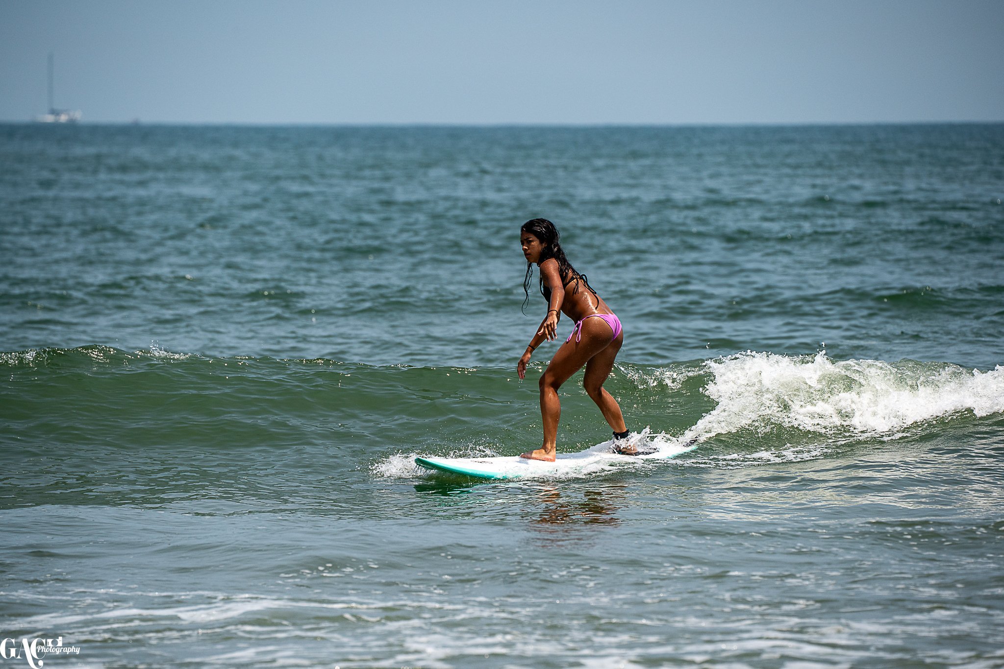 A woman in a pink bikini surfing on a wave in the ocean.
