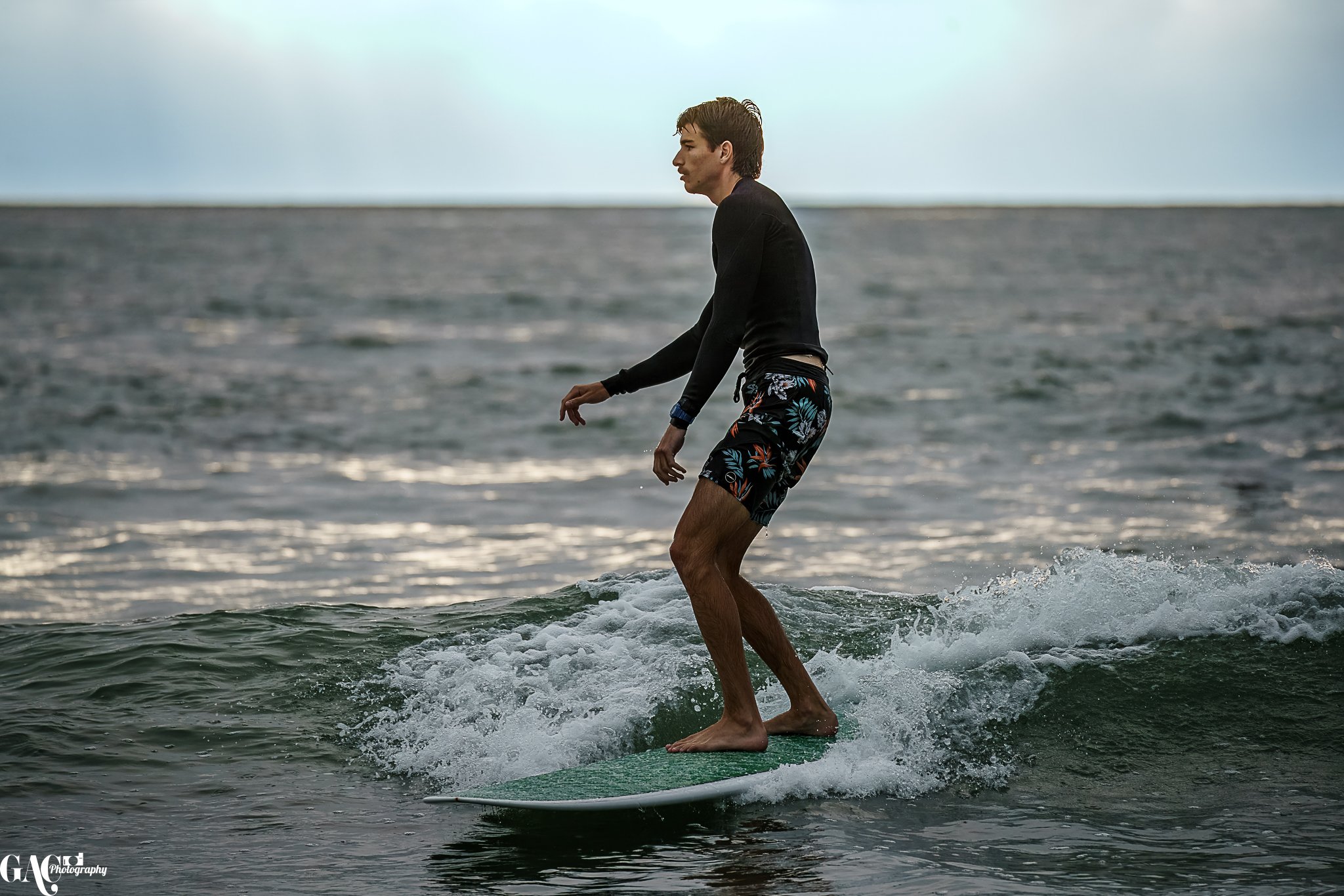 A young man surfing on a small wave in the ocean during daytime.