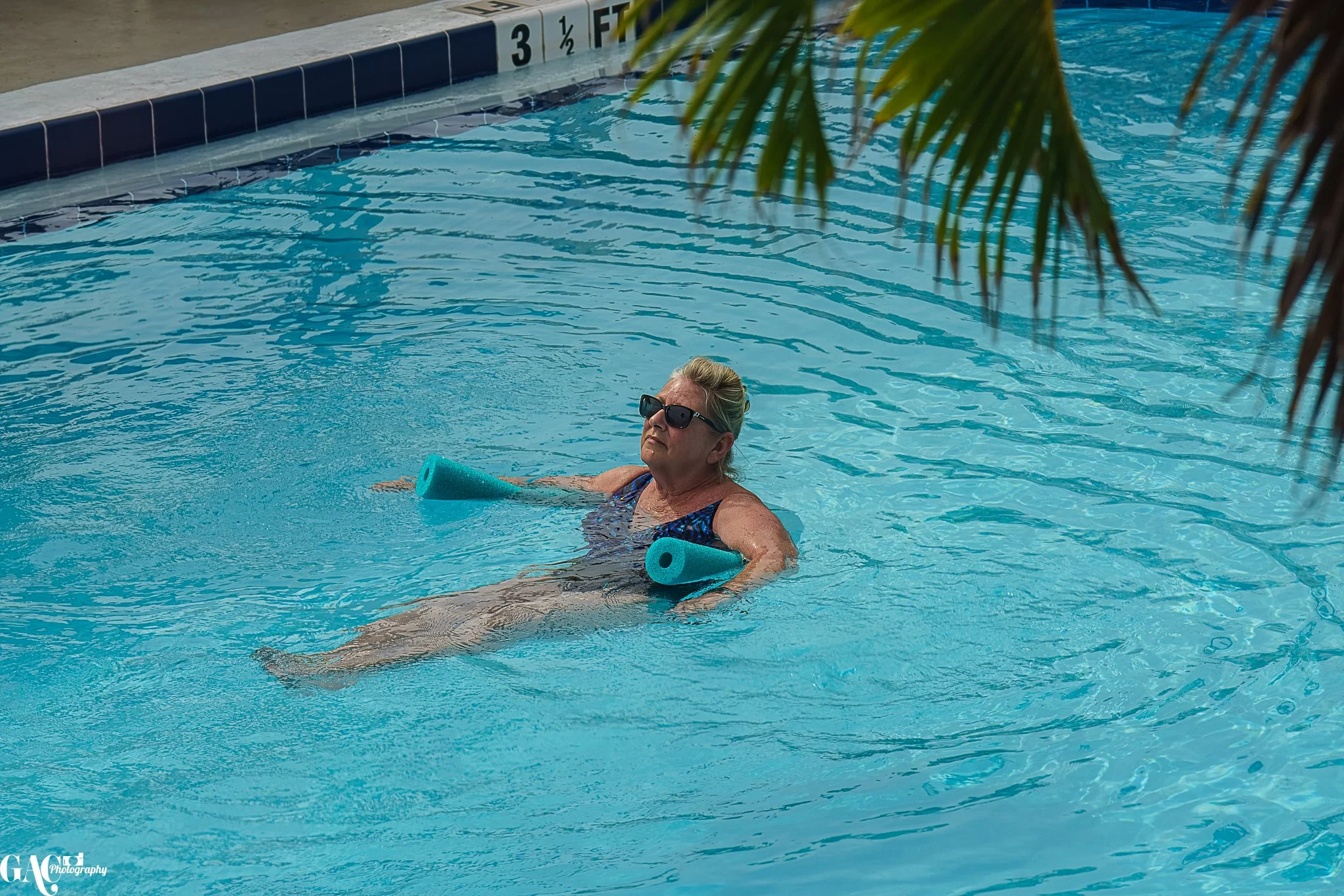 Woman relaxing in a swimming pool with foam noodles