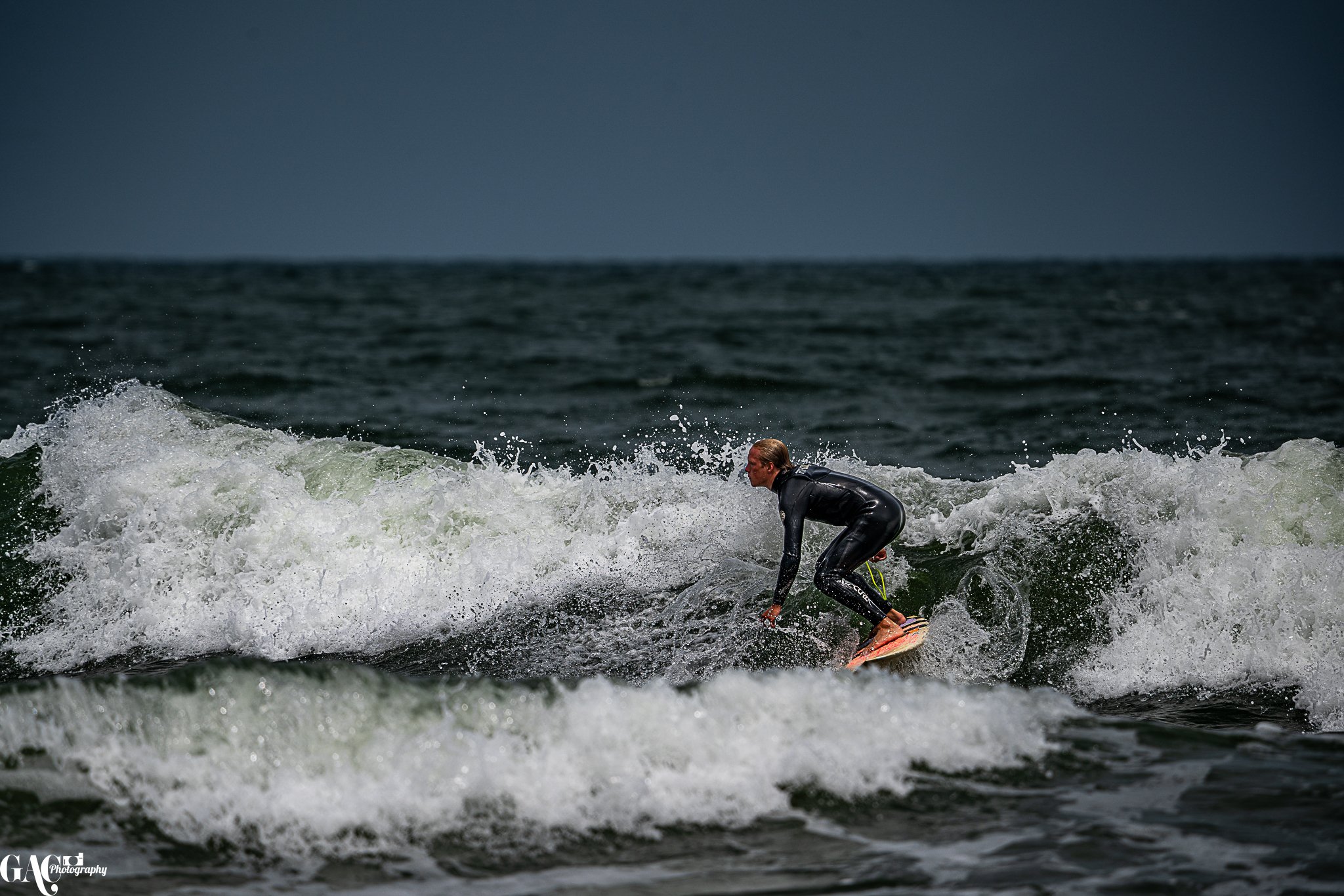 A person in a wetsuit surfing on a wave in the ocean.