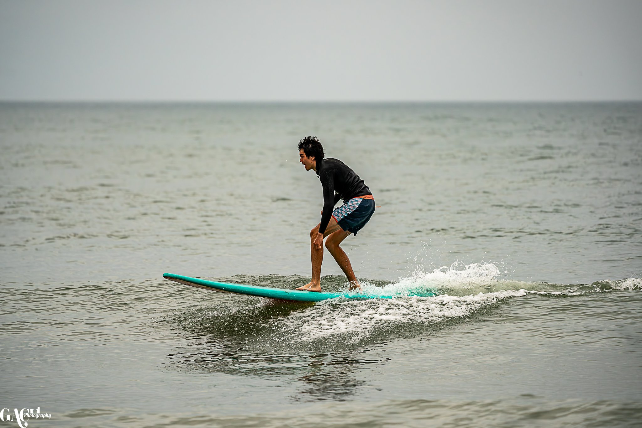 Young man riding a surfboard on calm ocean waters.