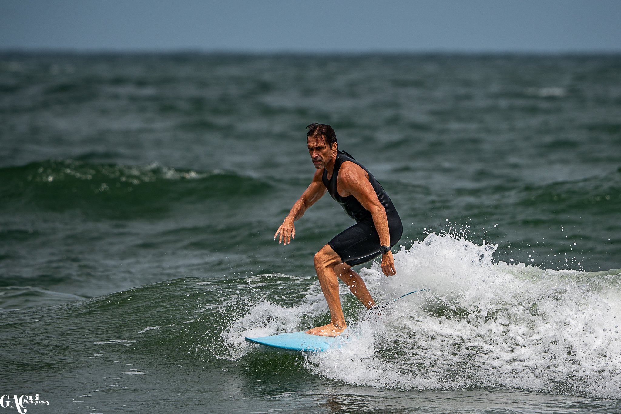 Man surfing on a blue surfboard in the ocean.