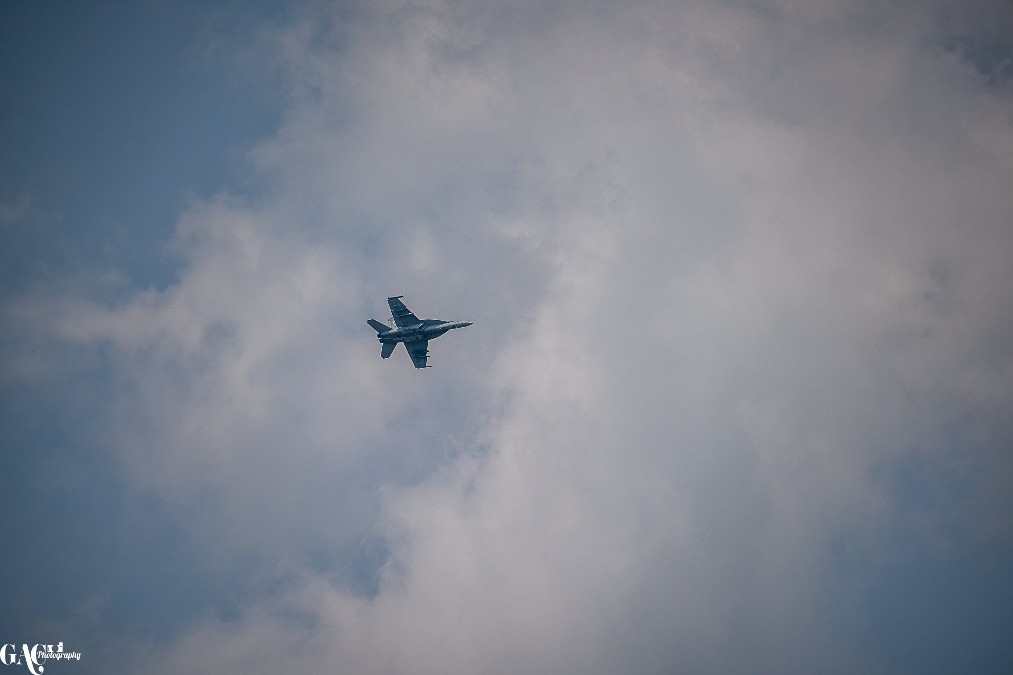 A fighter jet flying through the cloudy sky.