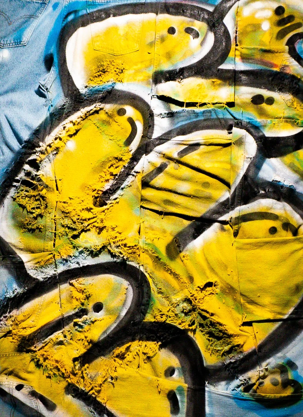 Close-up of a graffiti mural featuring yellow, black, white, and hints of blue colors, with abstract shapes and patterns.