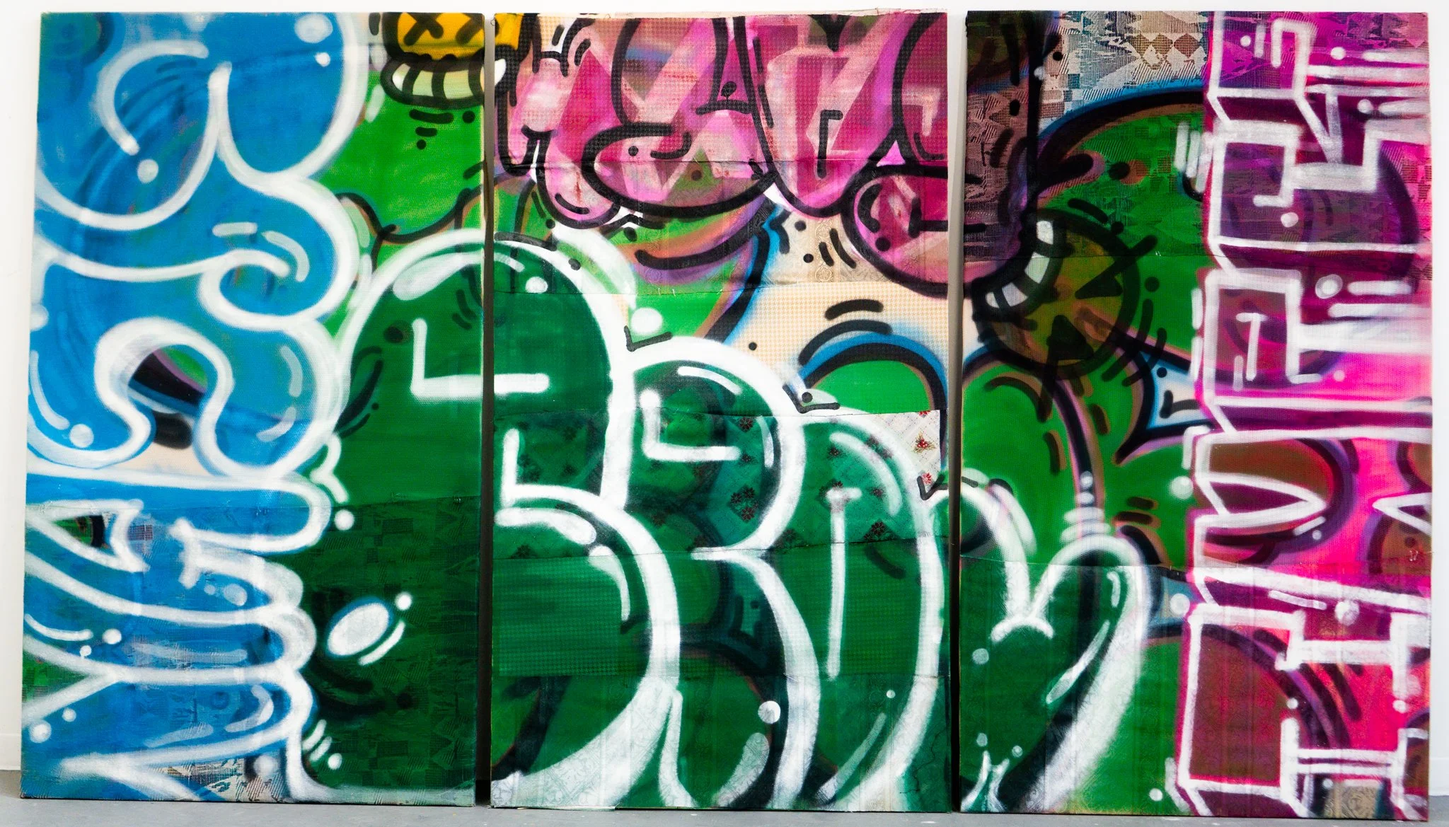 Colorful graffiti art on a wall with abstract shapes, letters, and vibrant colors including blue, green, pink, and purple.