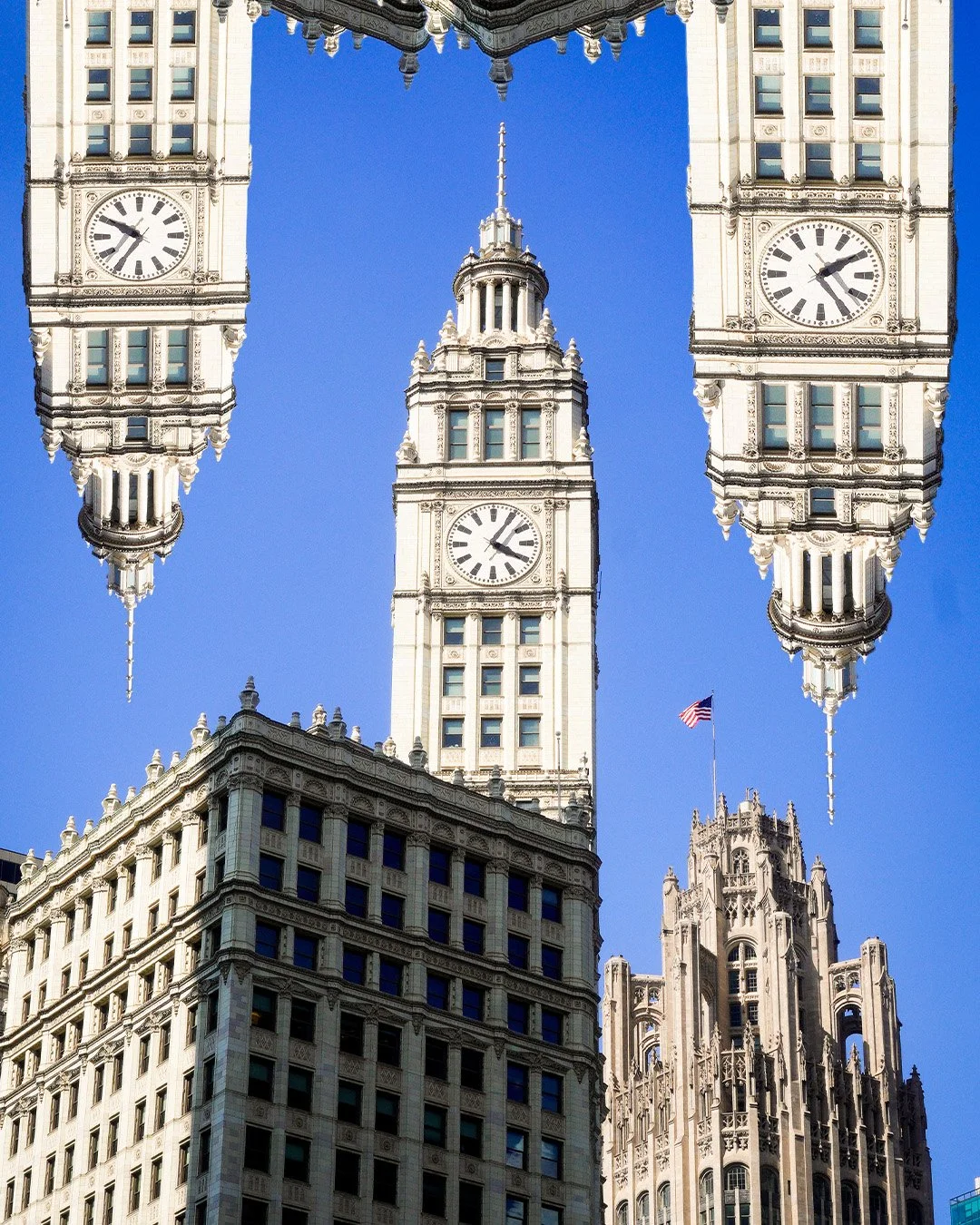 Multiple clock towers of a historic building with a clear blue sky background, including the Wrigley Building in Chicago, Illinois.
