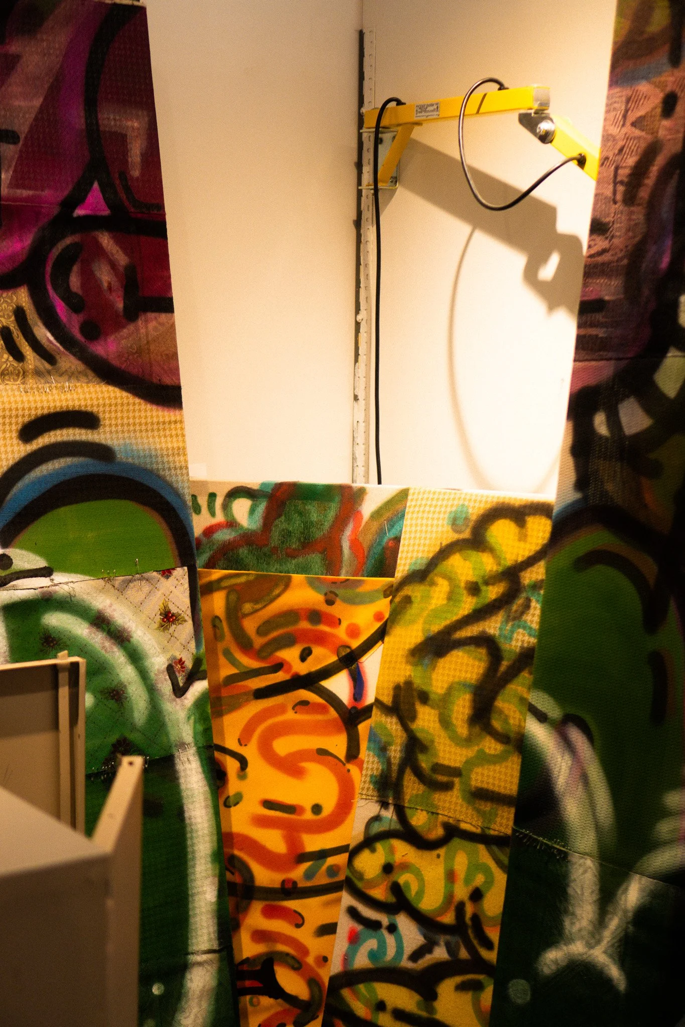 A collection of colorful, graffiti-style painted panels with various abstract designs and patterns, including swirls, lines, and shapes, displayed vertically and overlapping each other.