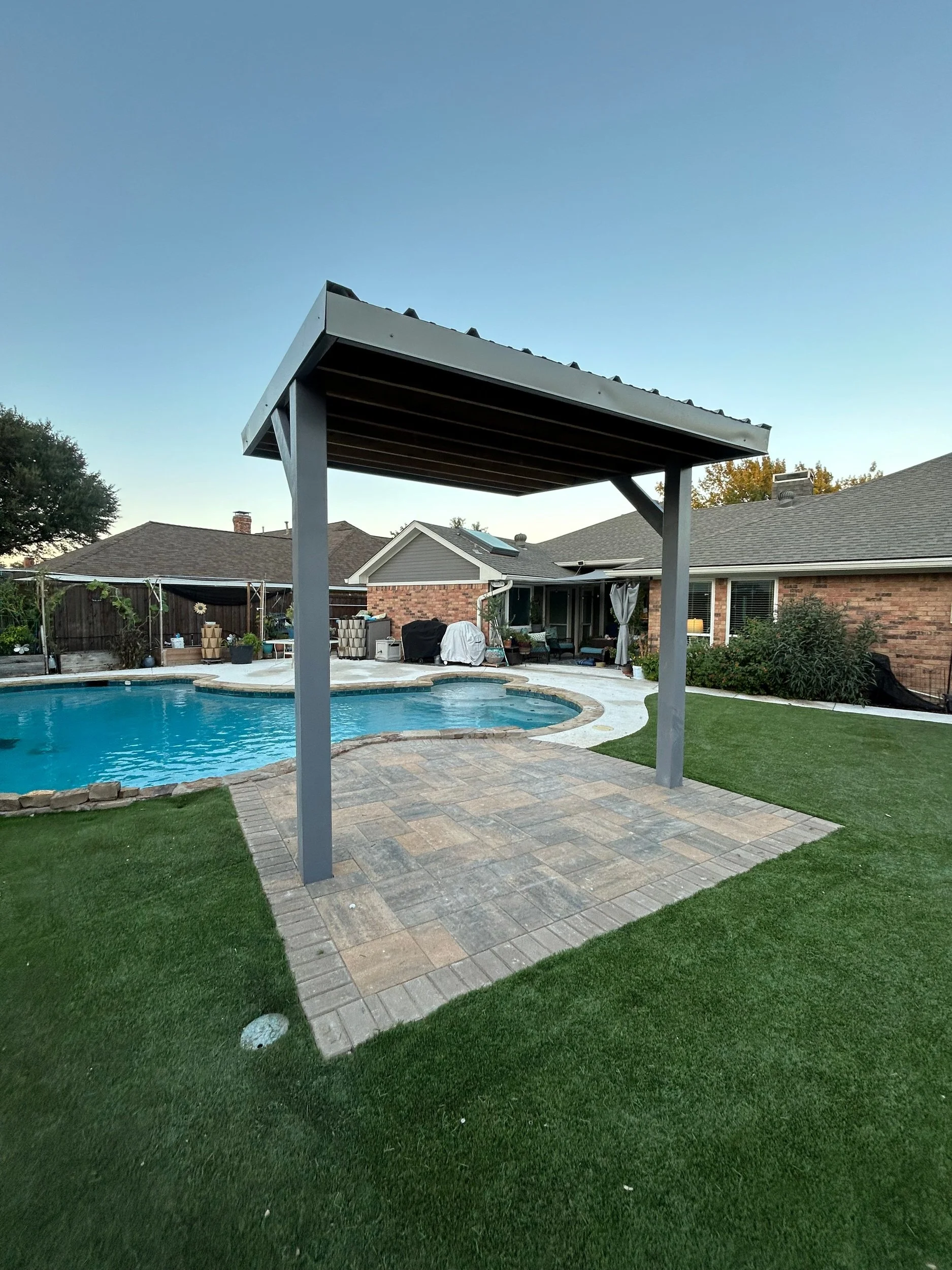 Metal patio cover installed beside residential swimming pool in Texas.