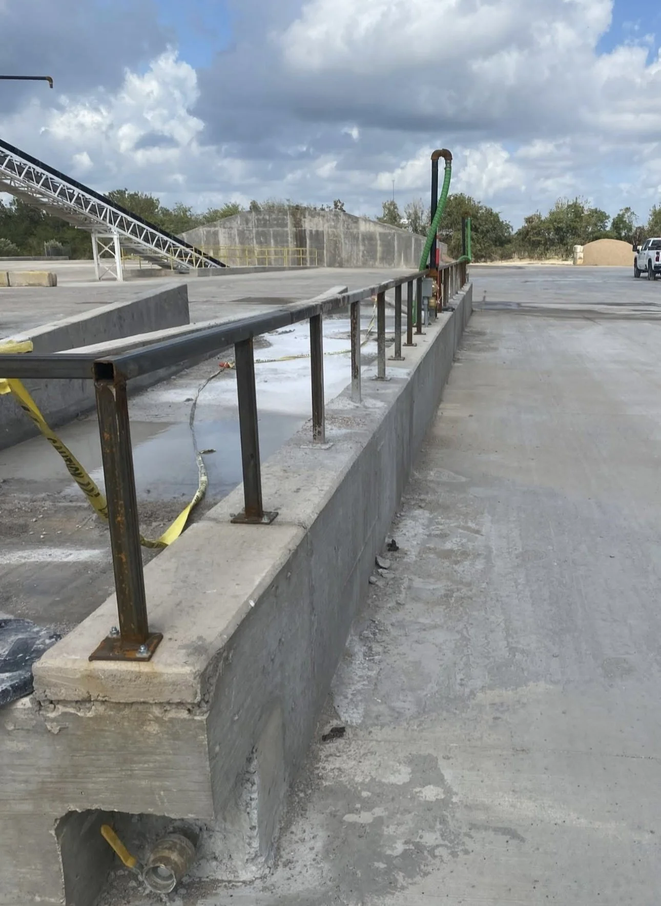 Metal safety railing installed along concrete curb at commercial site.