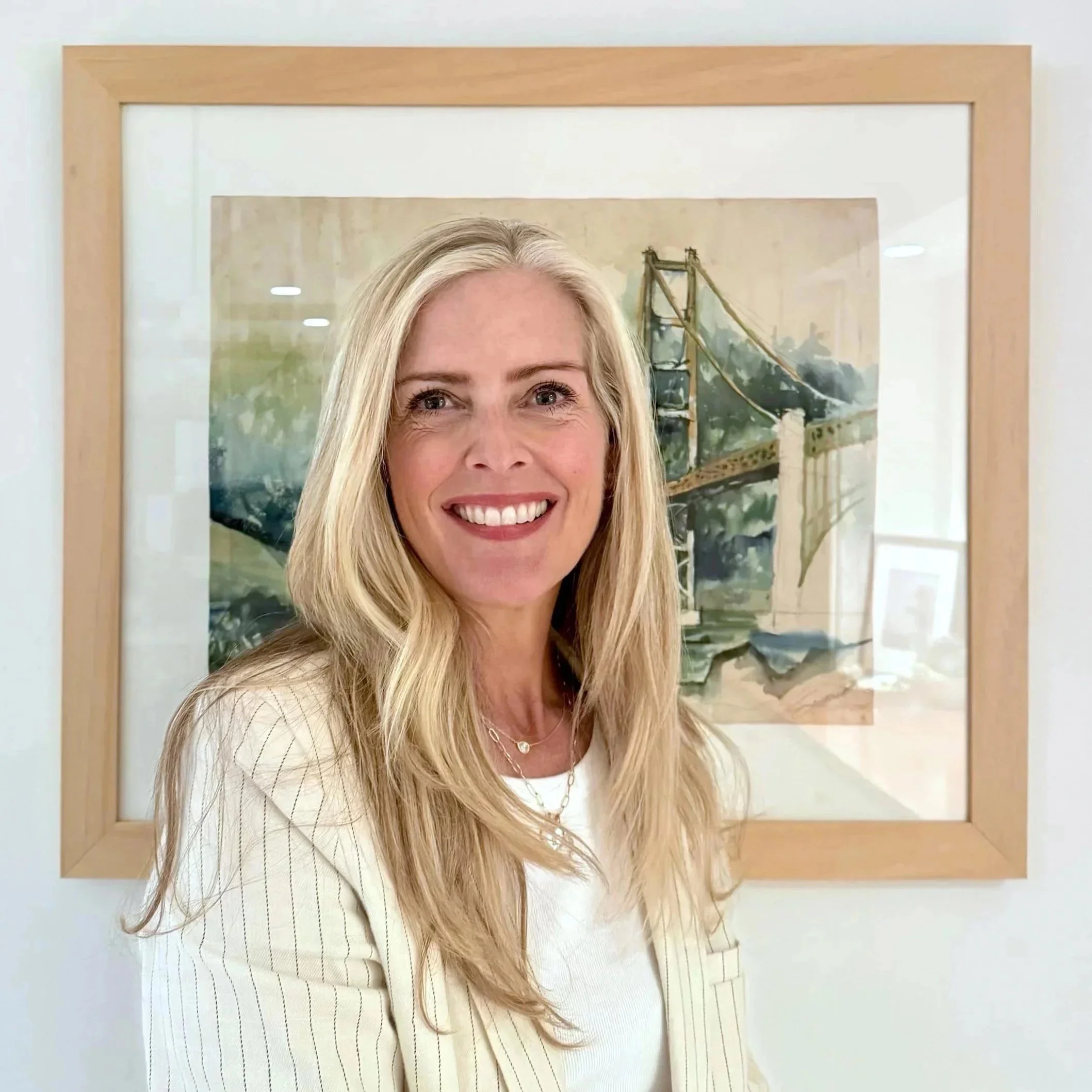 Arts consultant Laura Bradley smiling in front of a framed picture of the Golden Gate Bridge.
