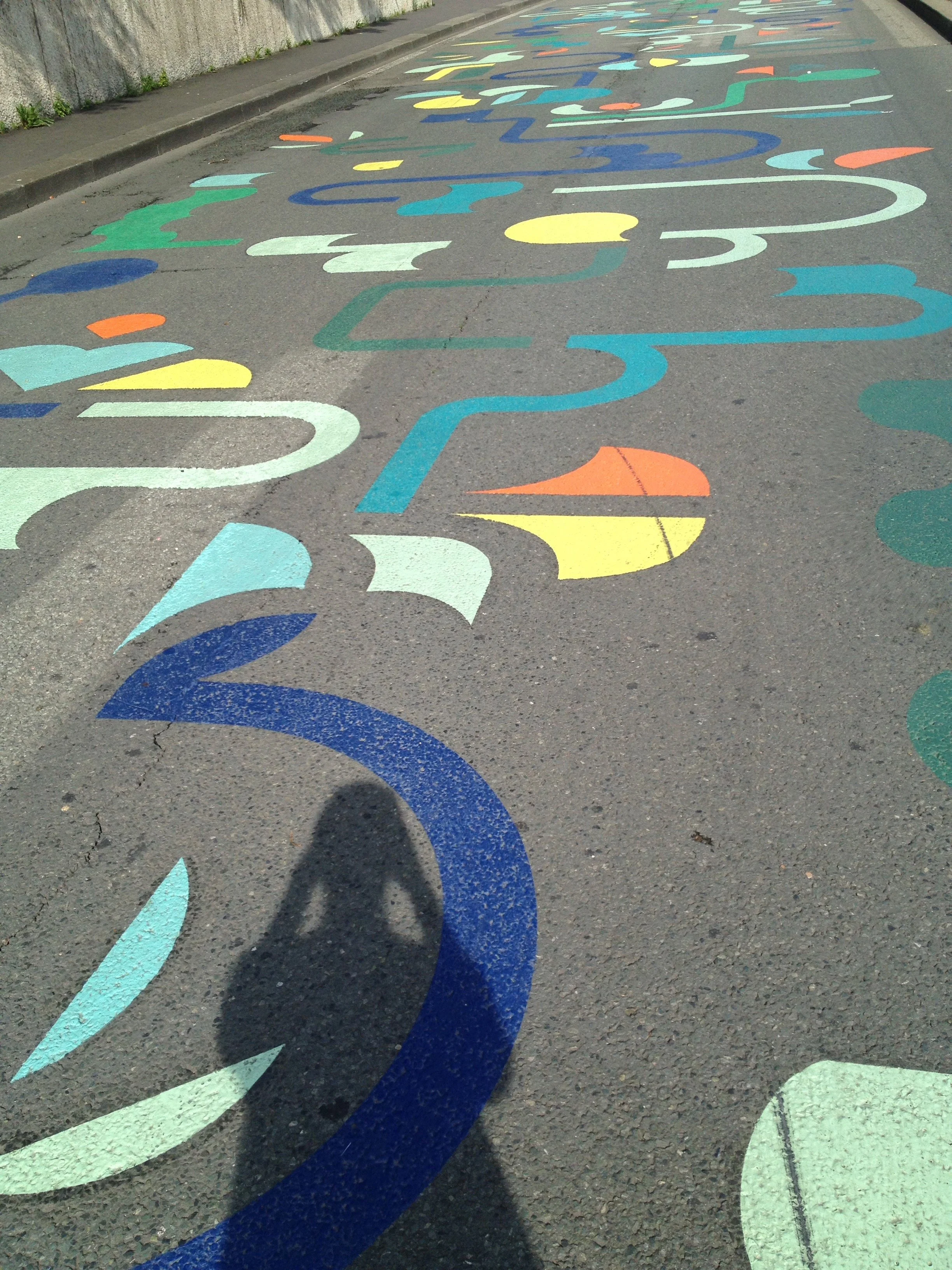 Colorful numbering painted on a street sidewalk, arranged in a sequence from 1 to 11, with varying directions and colors.