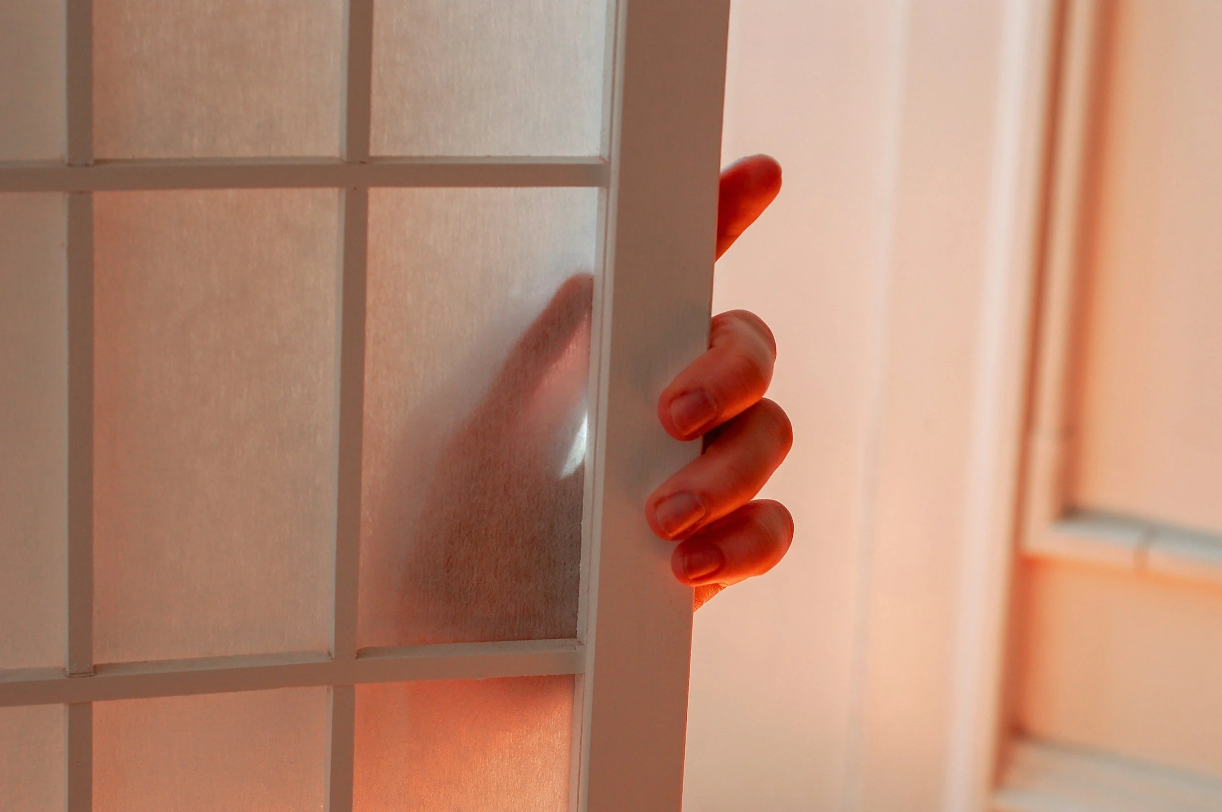 Person peeking through the slats of a white wooden vent cover.