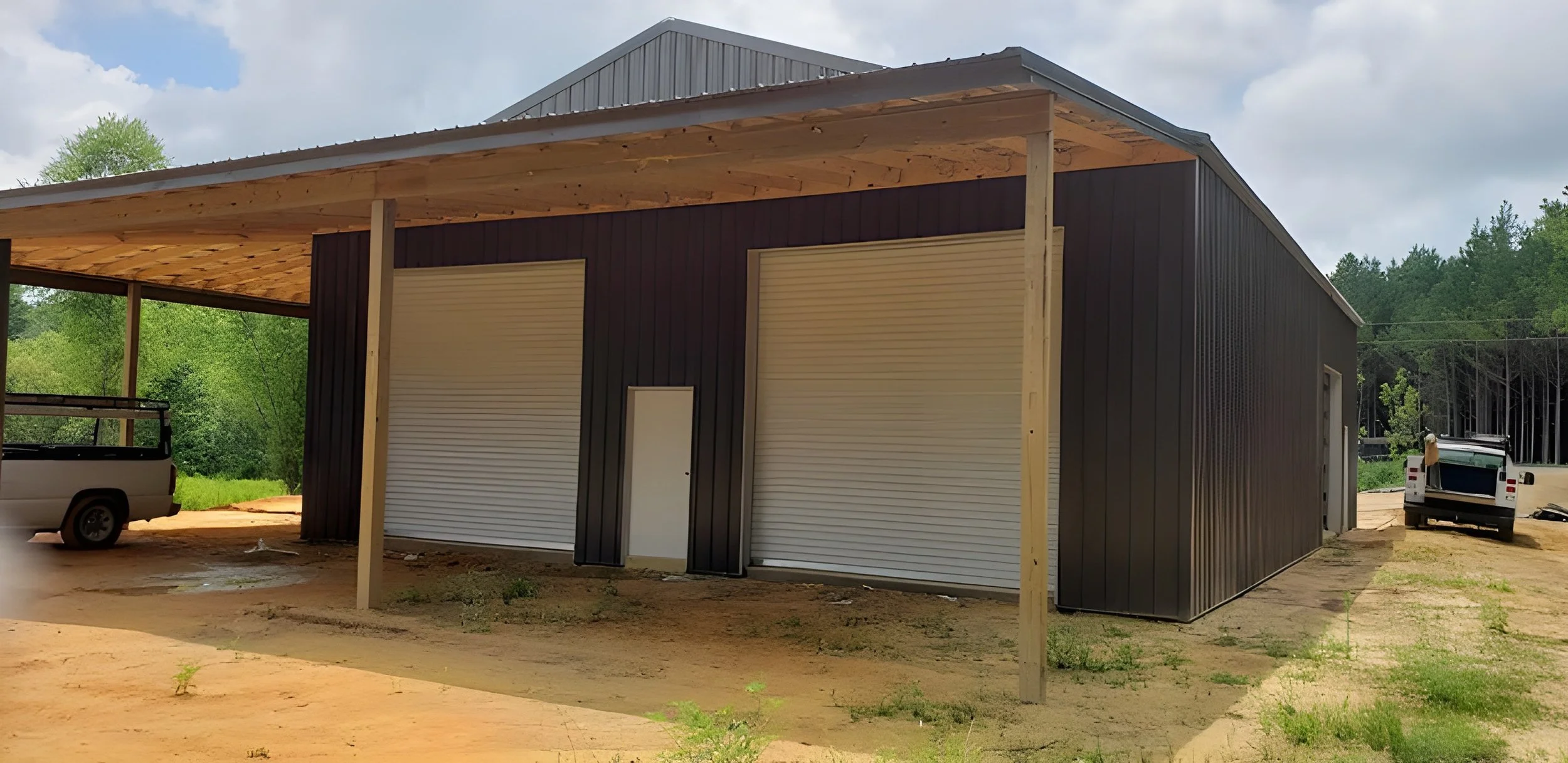 A new black metal building featuring a small door and two large roll-up garage doors.