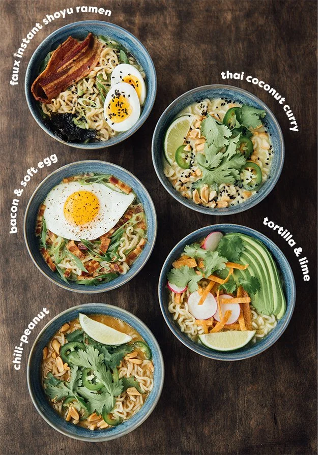 Five bowls of ramen with various toppings, including bacon, soft egg, peanuts, vegetables, lime, radishes, cilantro, and chili, arranged on a wooden table.