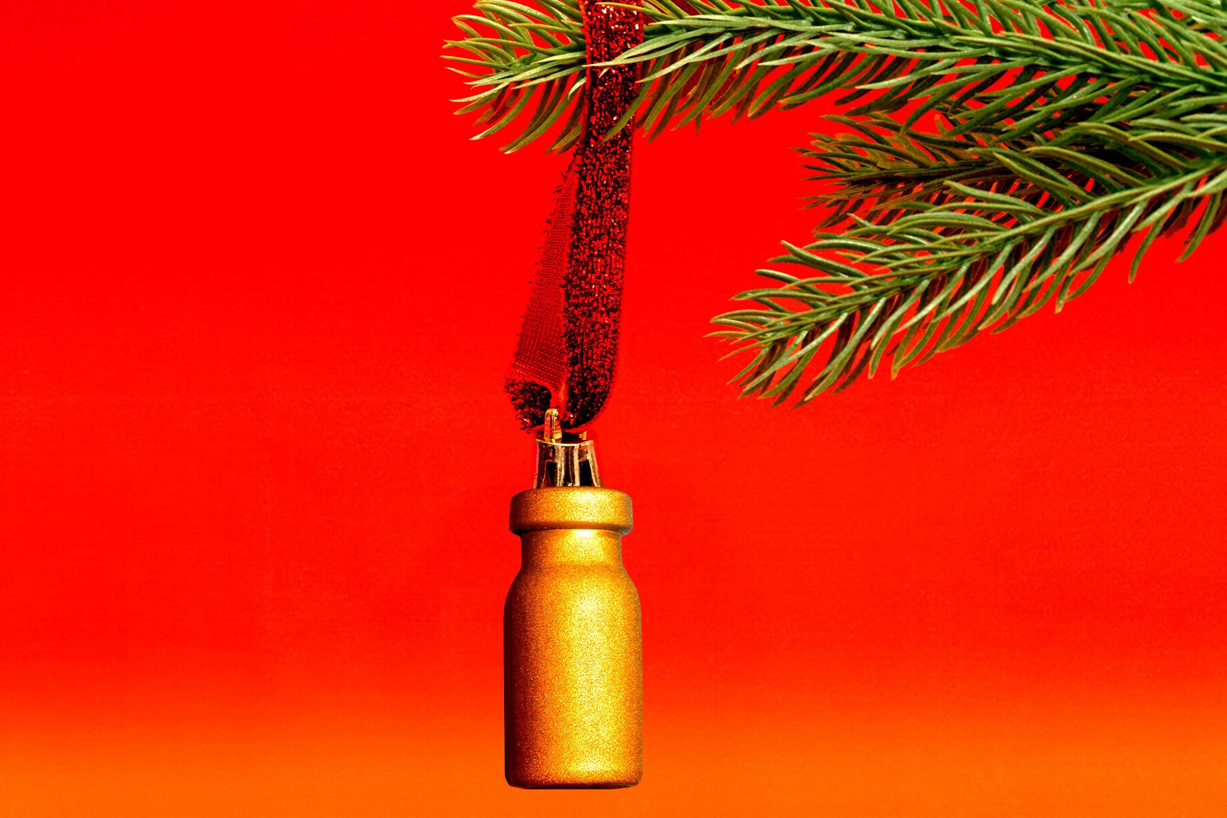 A Christmas tree ornament with a branch of a pine tree, set against a red background.