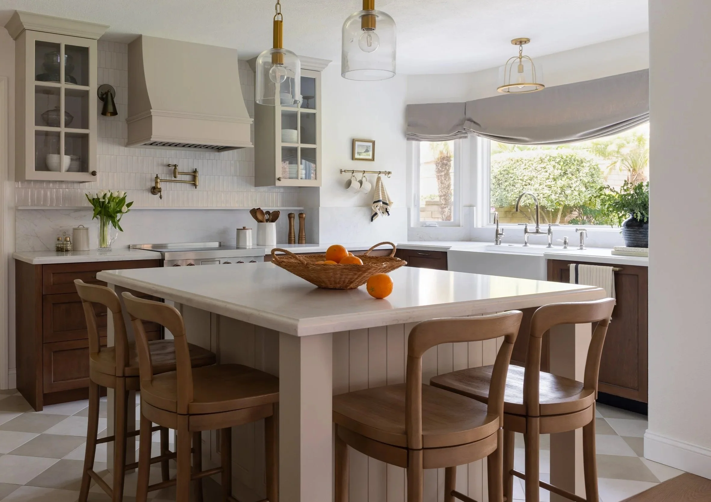 Transitional kitchen with island, custom hood, farmhouse sink, and brass pot filler, florals and decor.