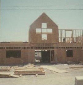 Front view of a building under construction with a cross-shaped window in the upper section.