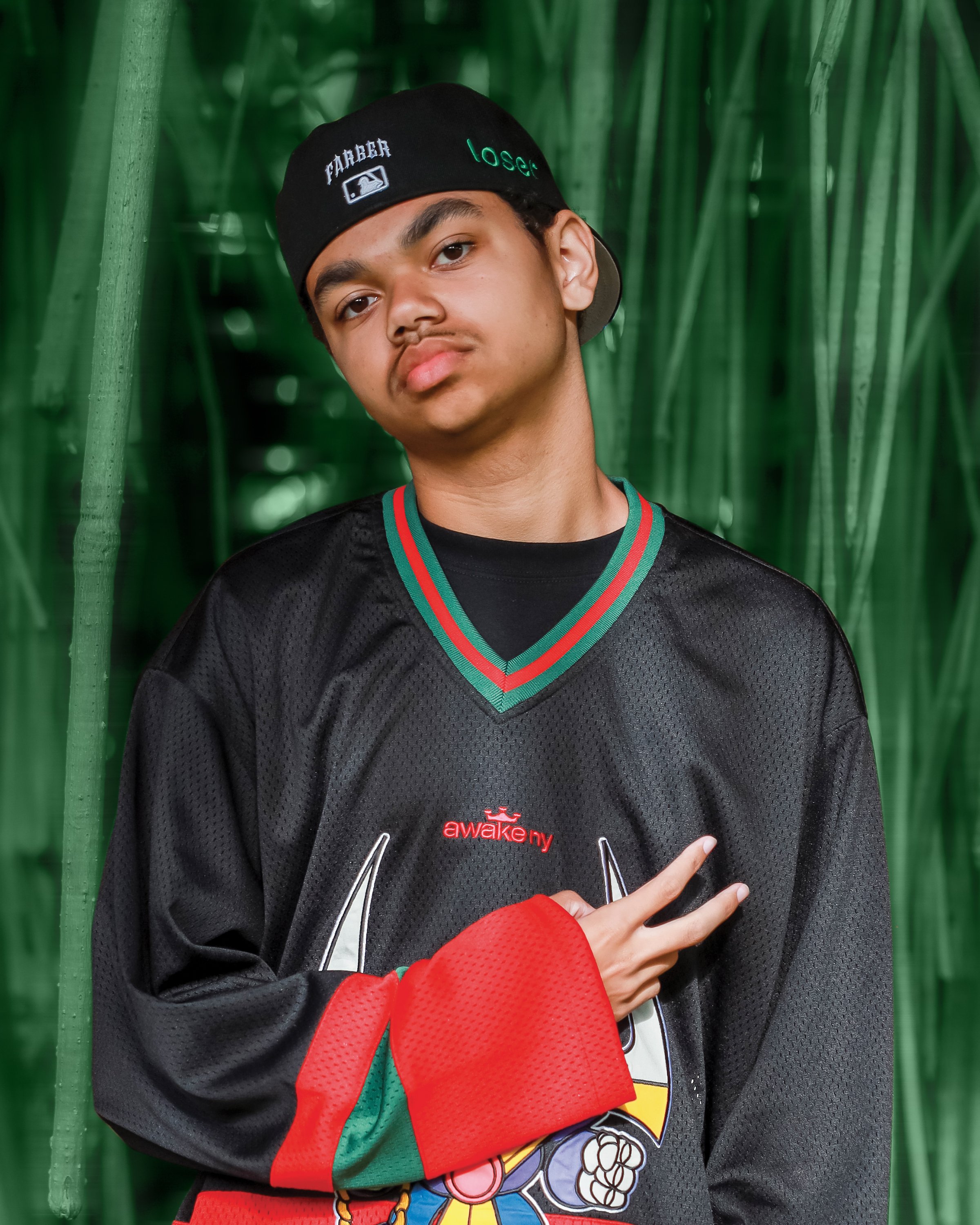 Farber wearing a black cap and colorful sweater with green background.
