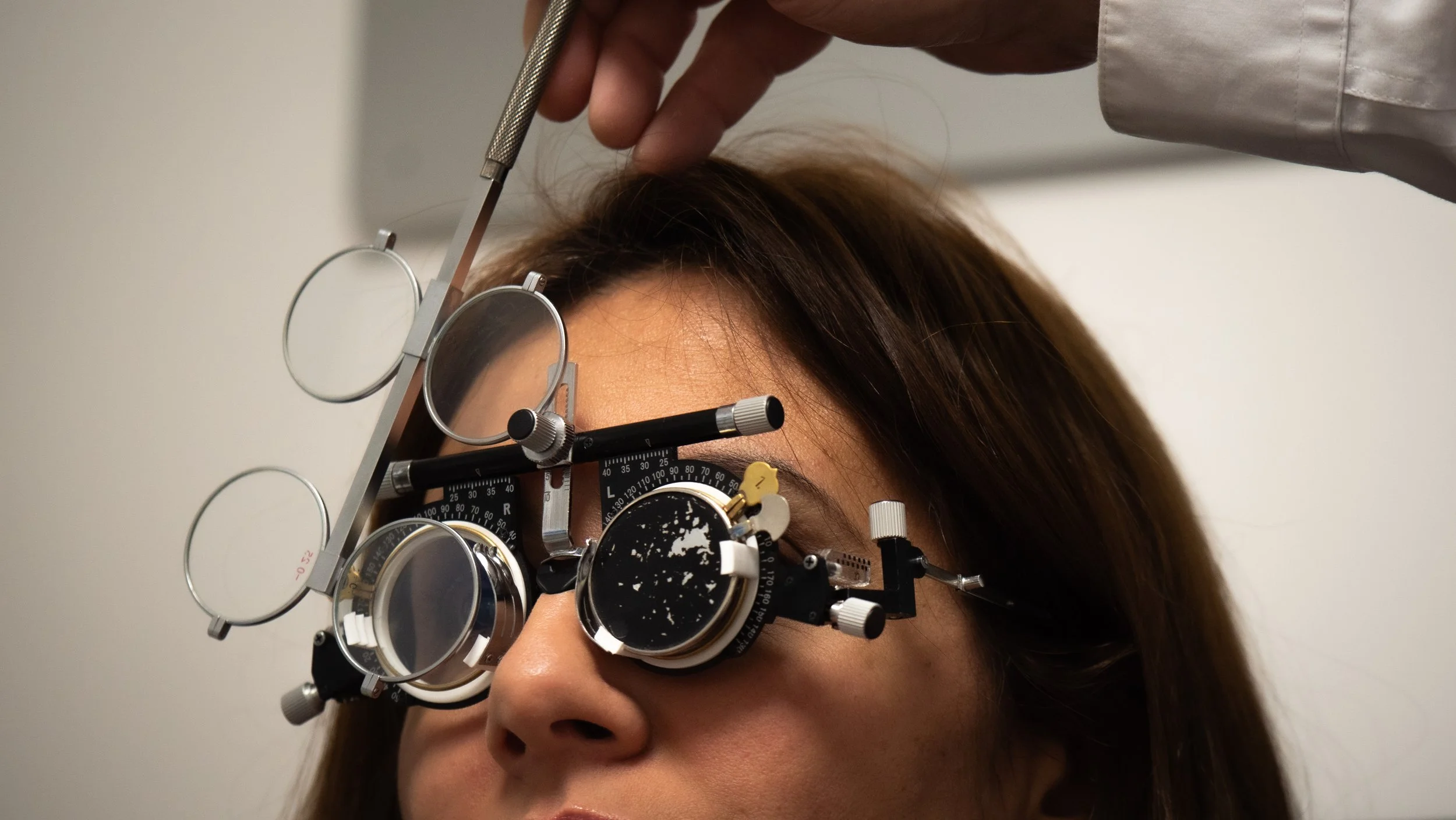 Une femme porte des lunettes ophtalmiques tout en étant examinée par un optométriste.