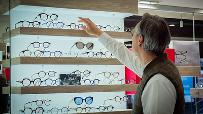 Un homme âgé fait du shopping pour des lunettes dans un magasin spécialisé.