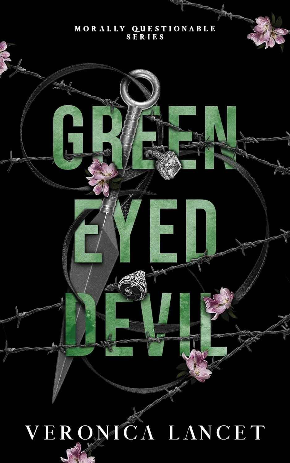 Book cover titled 'Green Eyed Devil' by Veronica Lancet, with barbed wire, pink flowers, a key, a ring, and a dagger on a black background.
