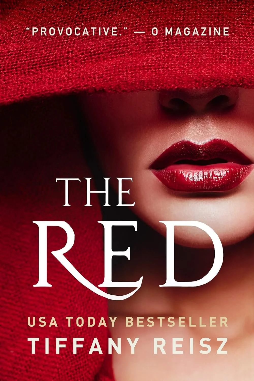 Close-up of a woman’s face with red lipstick, covered partially by a red textured fabric. The text on the cover reads ‘The Red’ by Tiffany Reisz, with a quote from O Magazine at the top.
