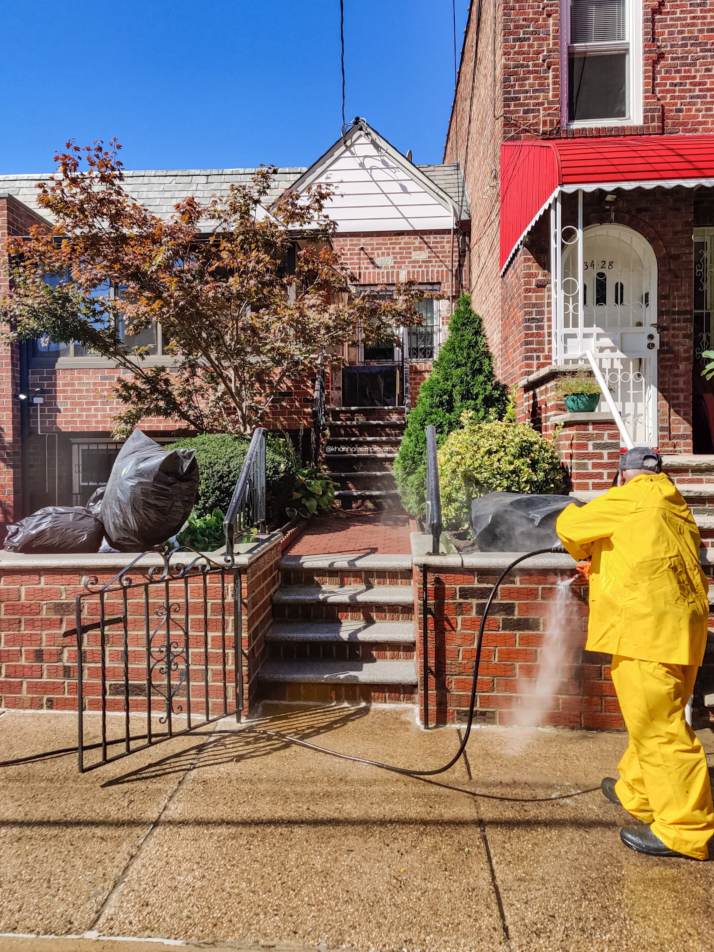 Pressure-washing a brick fence in Brooklyn under Khan Home Improvement.