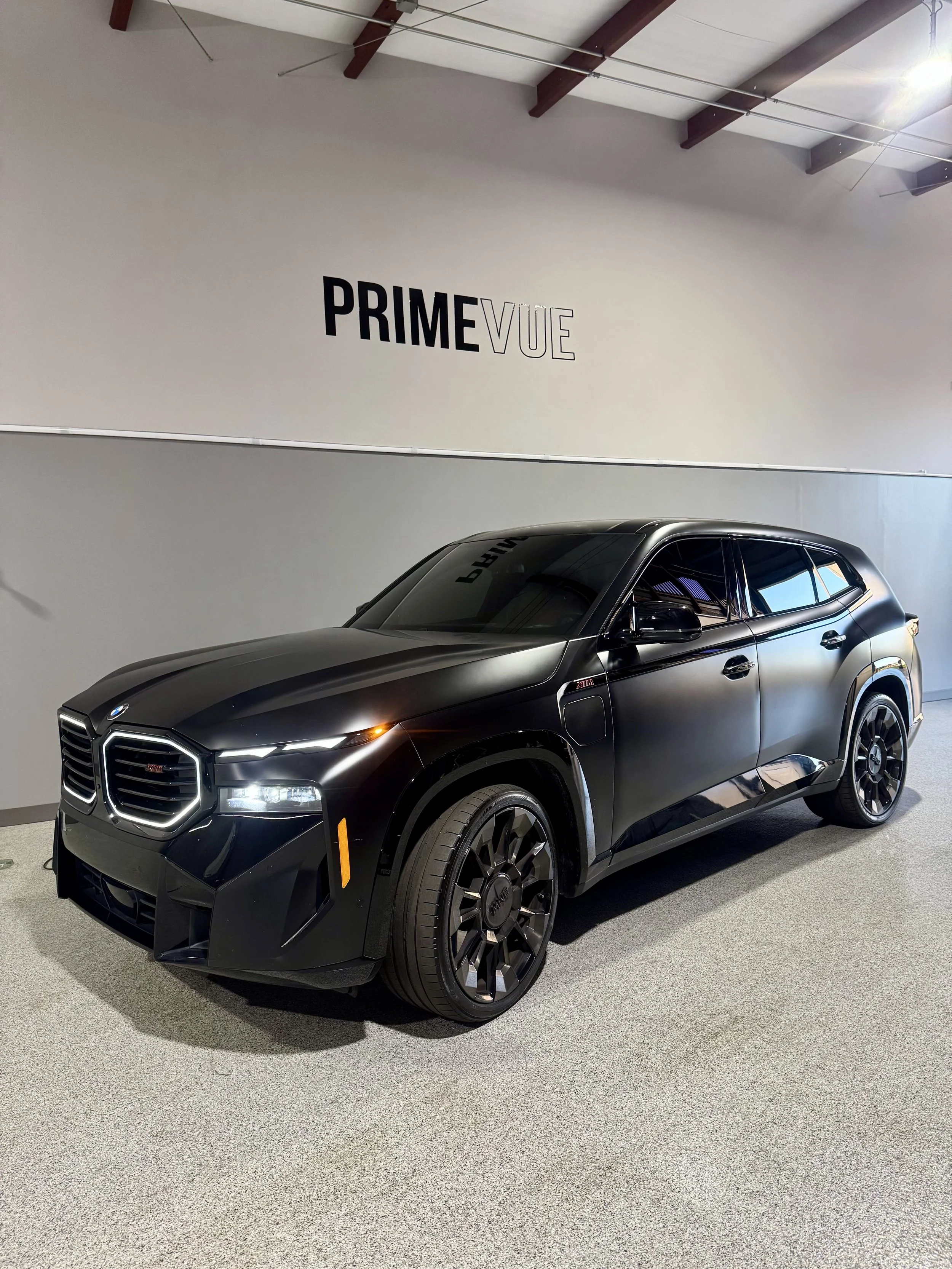 A black SUV parked indoors with windows tinted at PrimeVue.