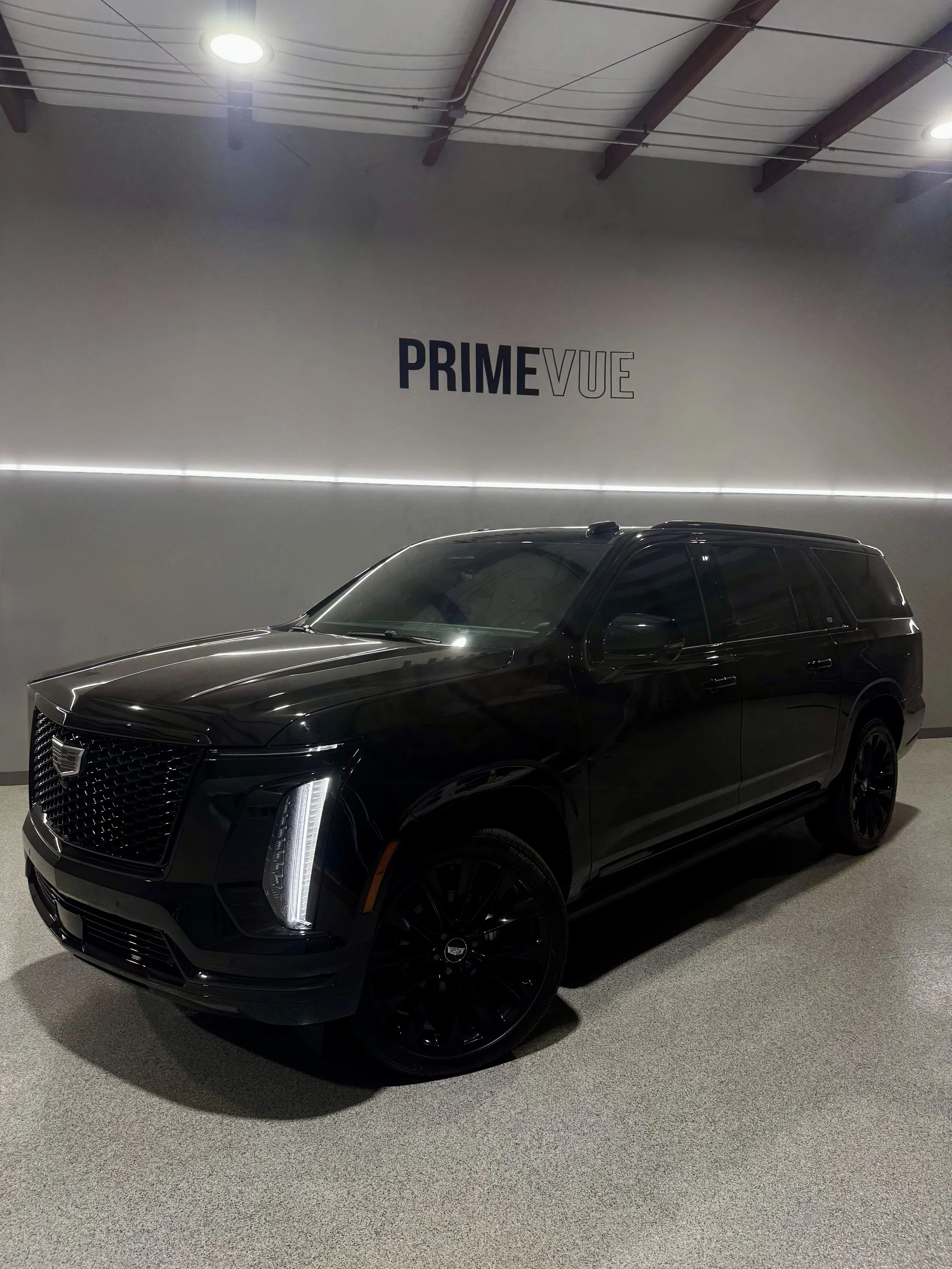 A black luxury SUV parked indoors getting windows tinted at PrimeVue.