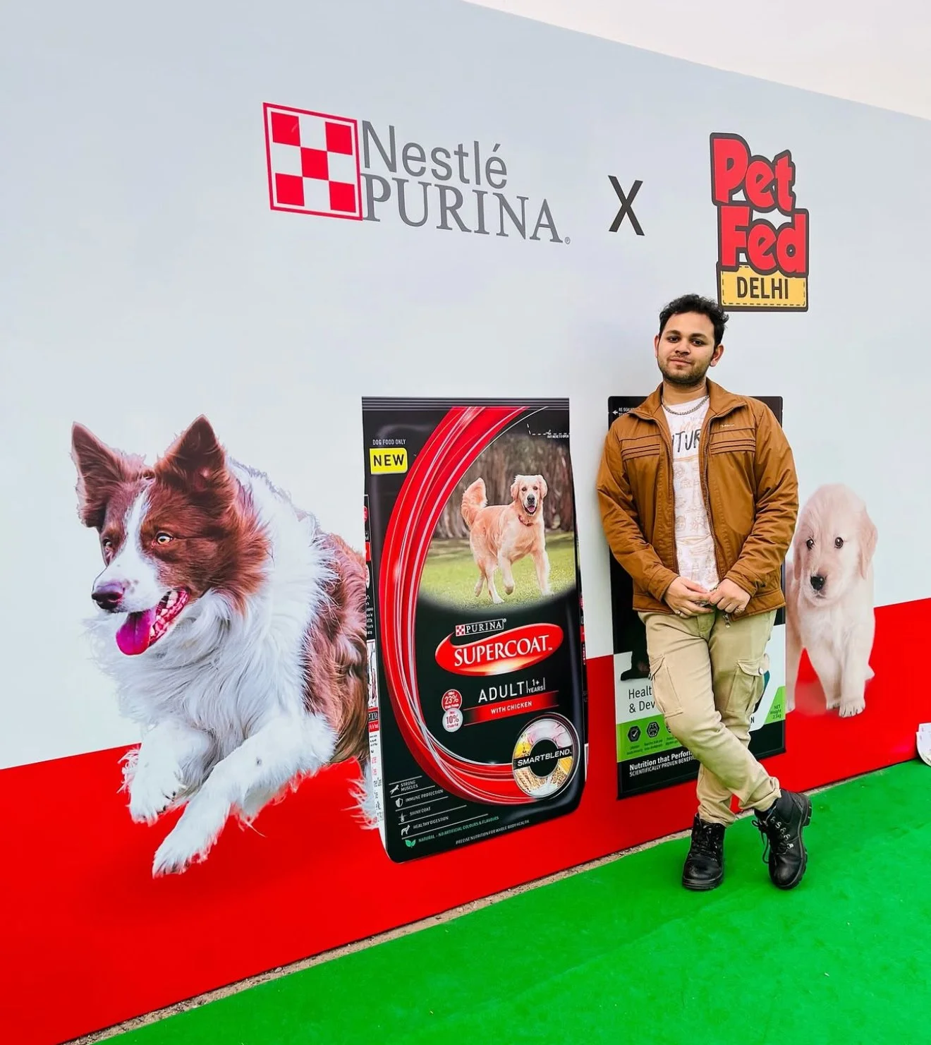 Person standing next to a Nestlé Purina and Pet Fed Delhi promotional backdrop featuring images of dogs and dog food packaging.