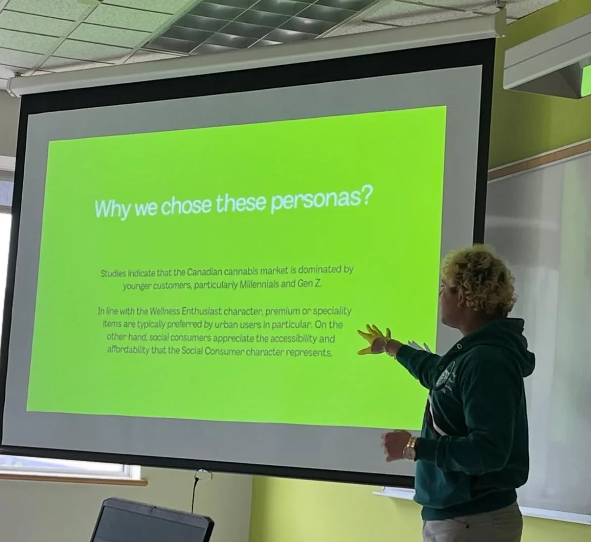 Person presenting a slide titled 'Why we chose these personas?' about the Canadian cannabis market, focusing on Millennials and Gen Z preferences, in a classroom setting.