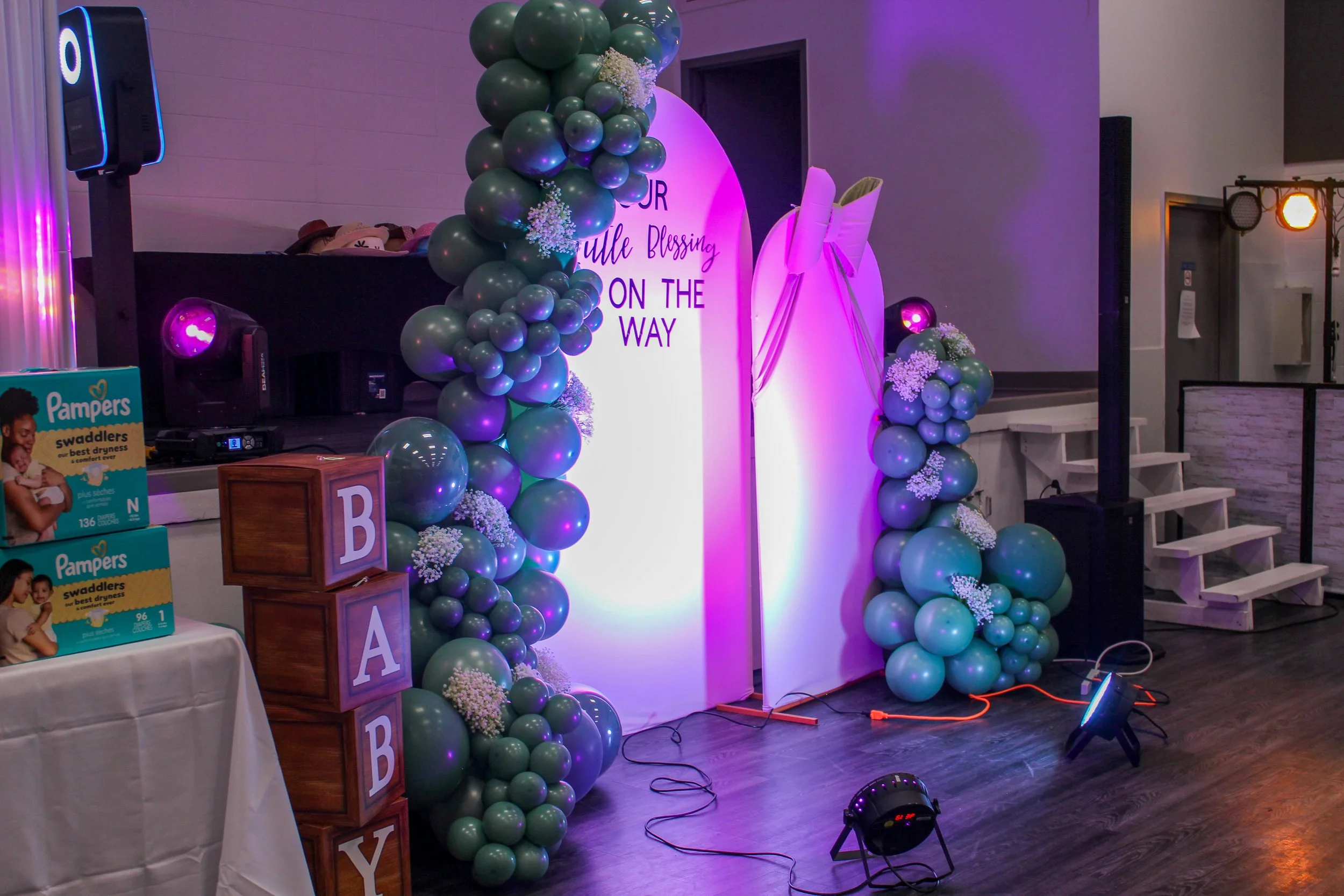 Decorative event display with balloon arch, signs, and lighting.