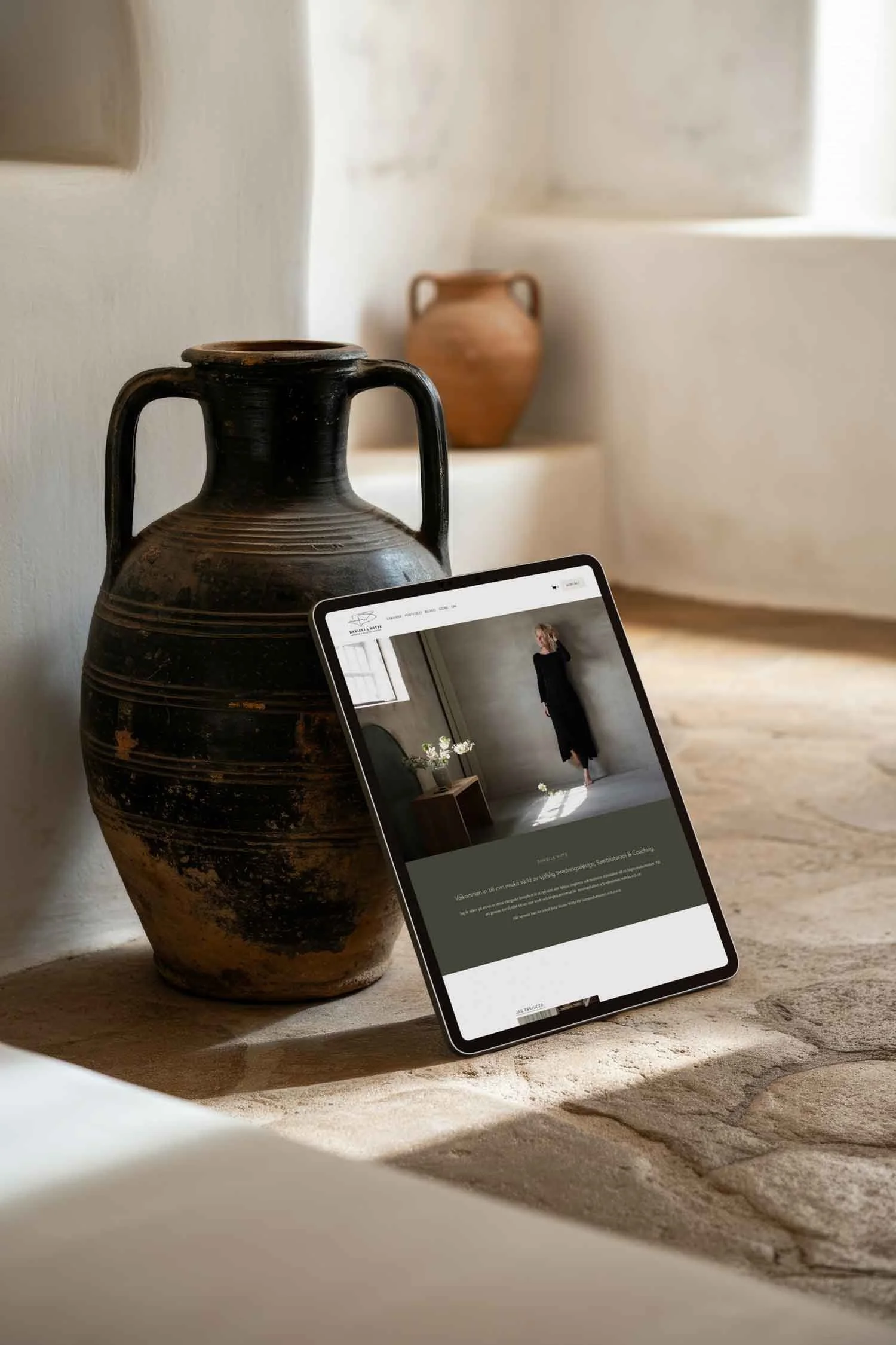 Två krukor, en iPad lutar mot ena krukan med Daniella Wittes hemsida på skärmen.