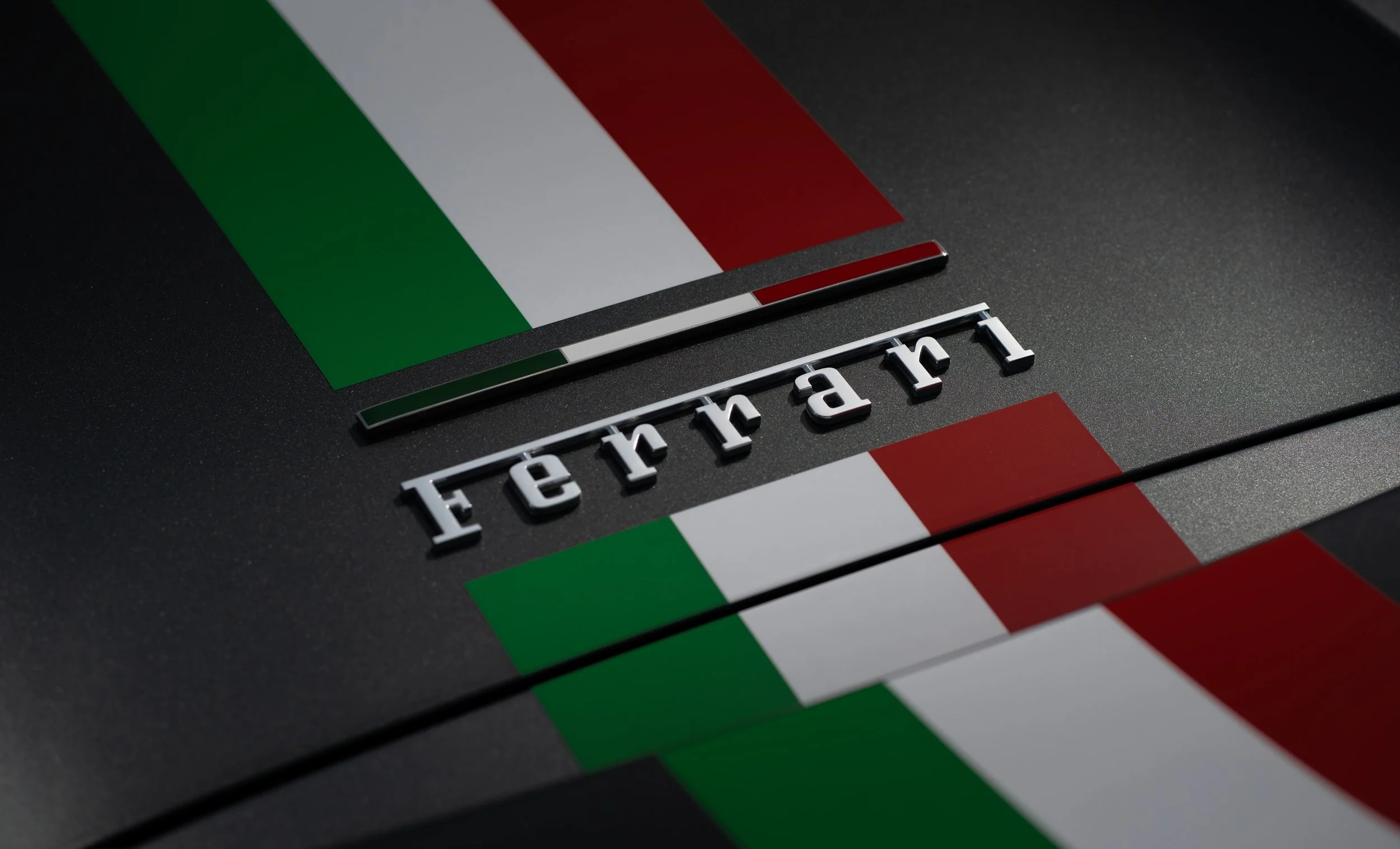 Ferrari logo on a black surface with Italian flag stripes.