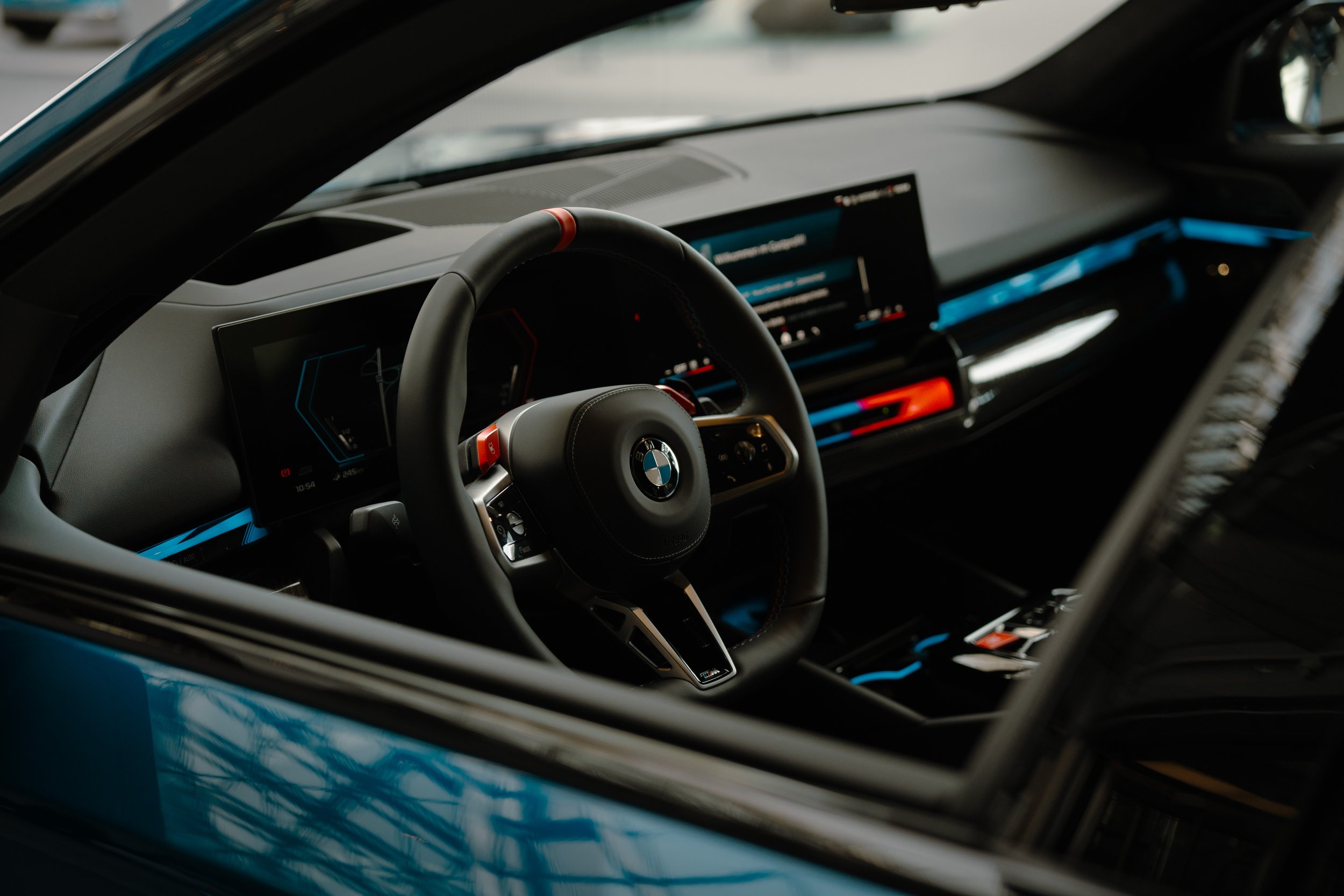 Interior of a BMW car, focusing on the steering wheel and digital dashboard display.